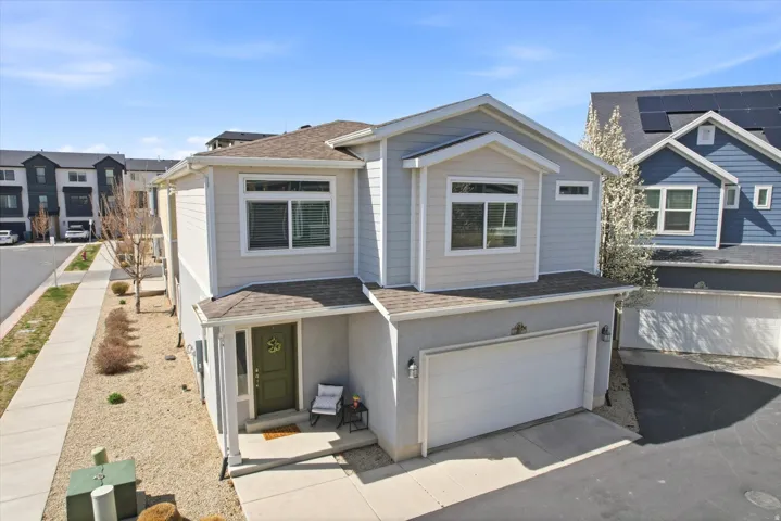 View of front of property featuring a shingled roof, an attached garage, driveway, and stucco siding