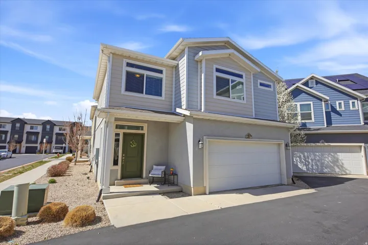 View of front of home with a garage, stucco siding, and asphalt driveway