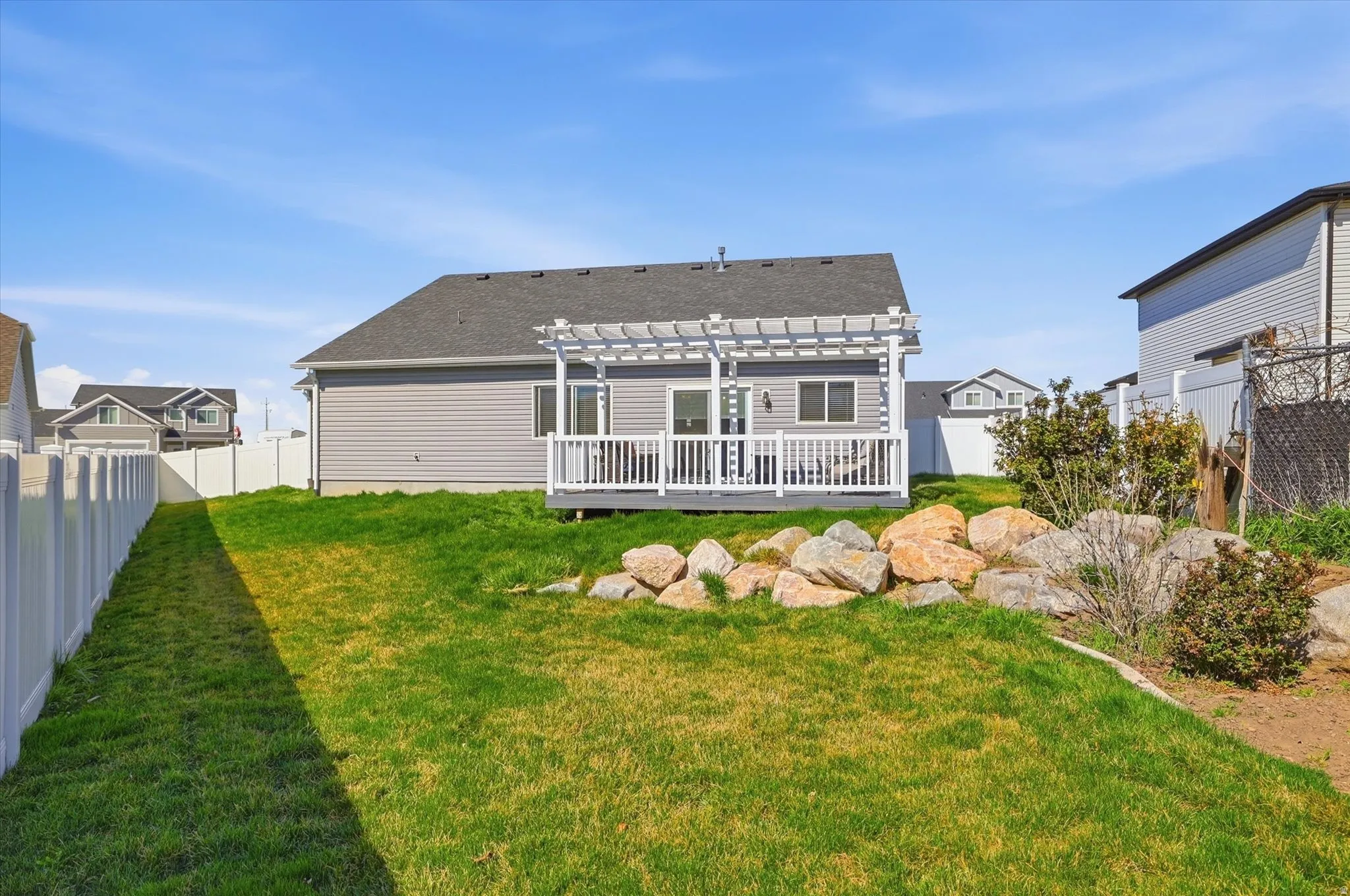 Back of house featuring roof with shingles, a fenced backyard, a pergola, and a deck