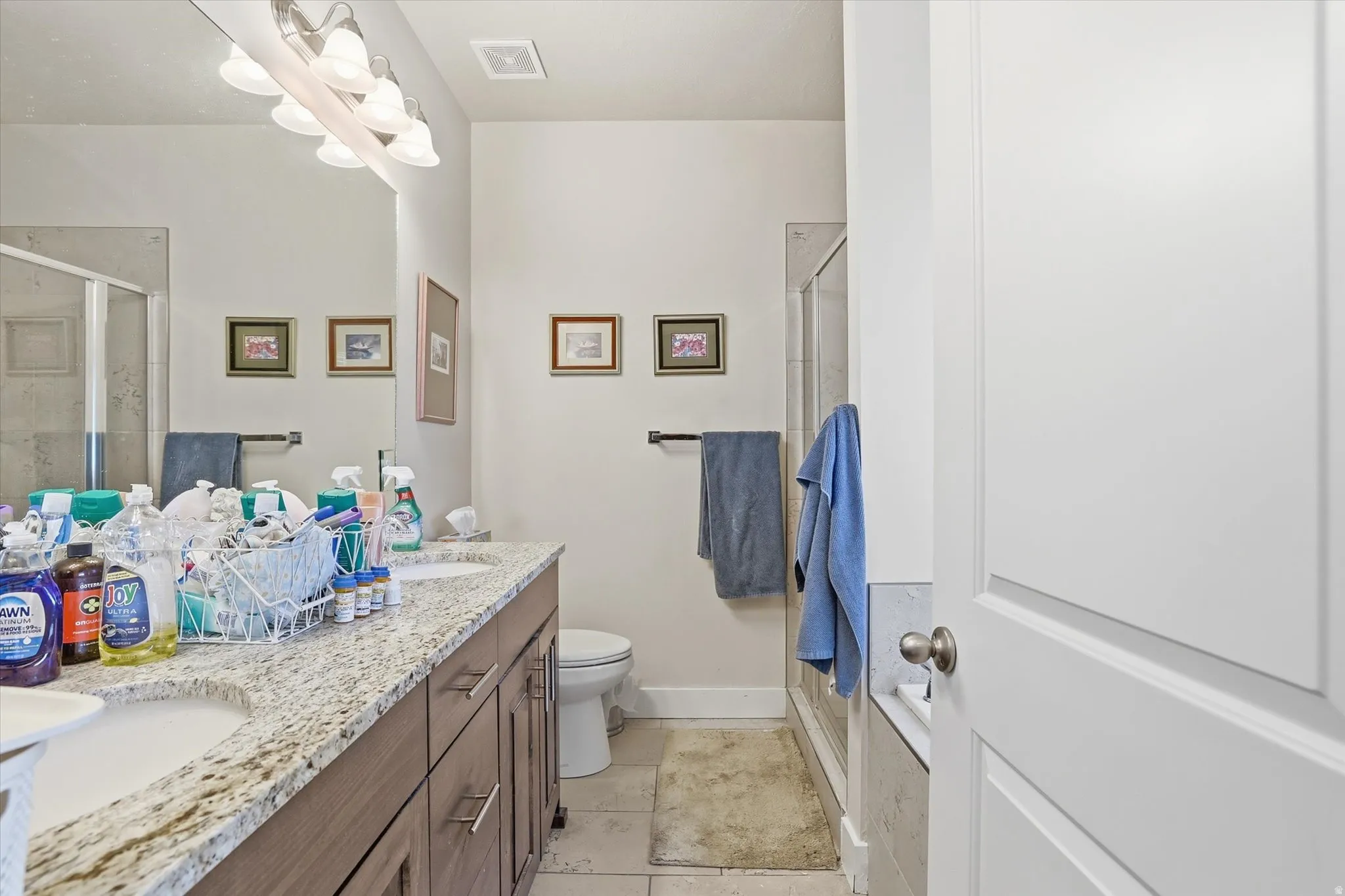 Full bath with an enclosed shower, double vanity, and light tile patterned floors