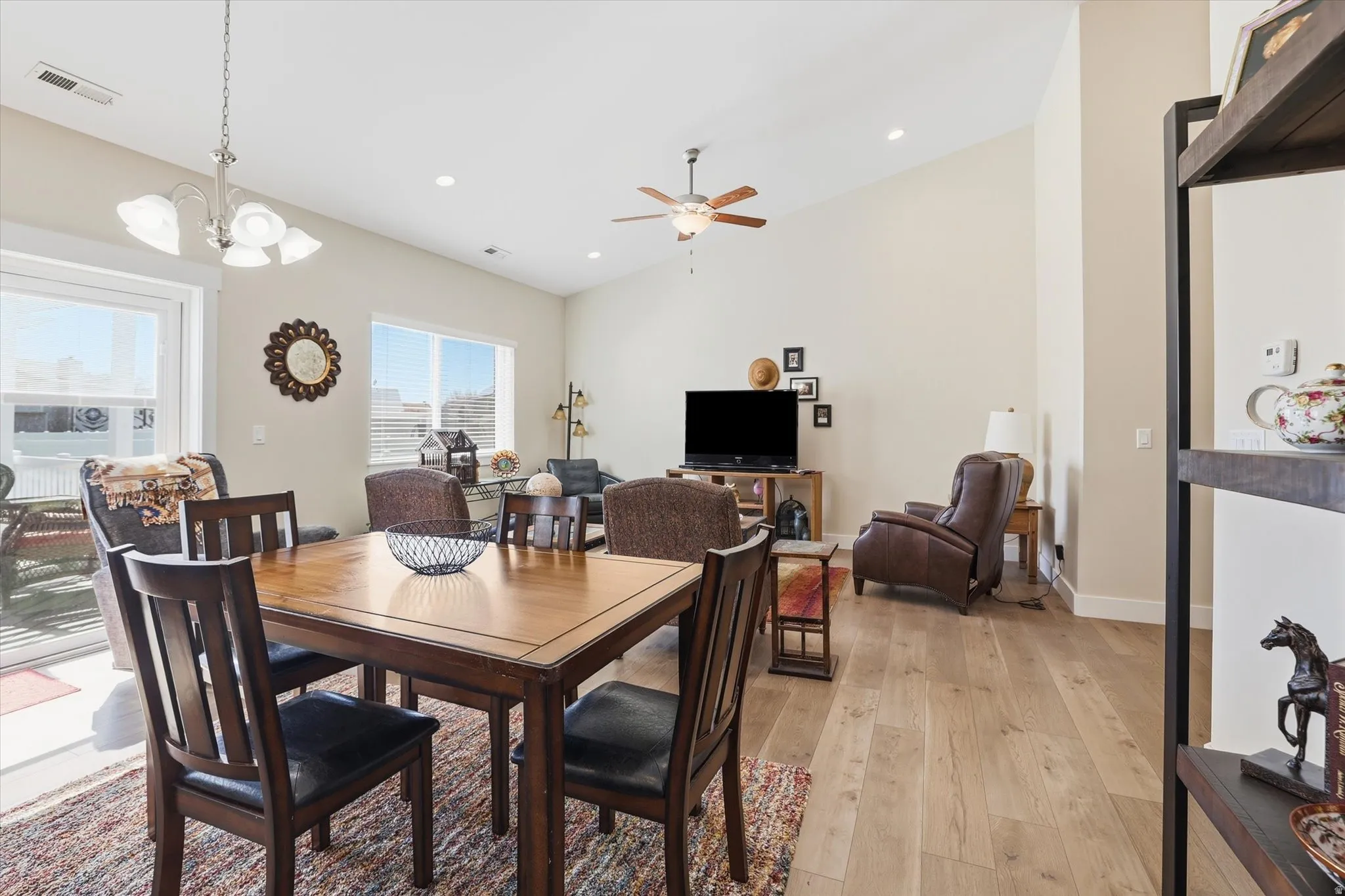 Dining room featuring light wood-style flooring, hanging lights, vaulted ceiling, and a ceiling fan