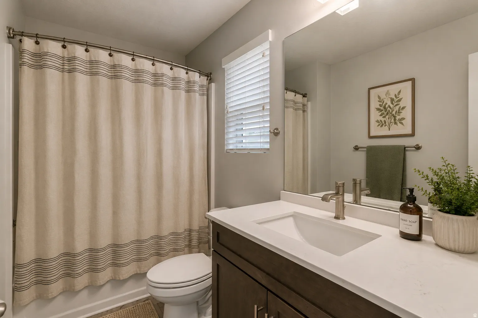 Virtually stage Bathroom featuring a vanity with an integrated sink, a brushed nickel faucet, and a large wall-mounted mirror