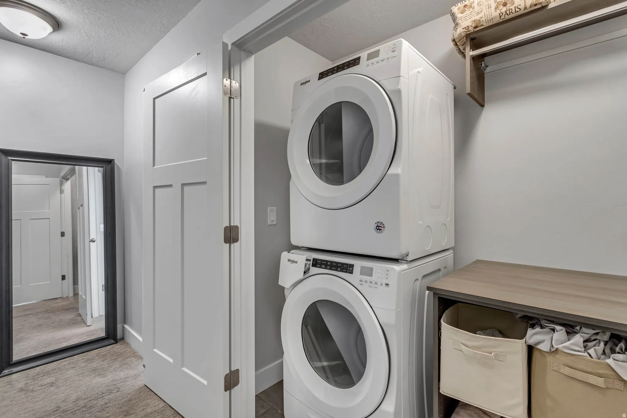 Laundry area featuring stacked washer and clothes dryer and a textured ceiling