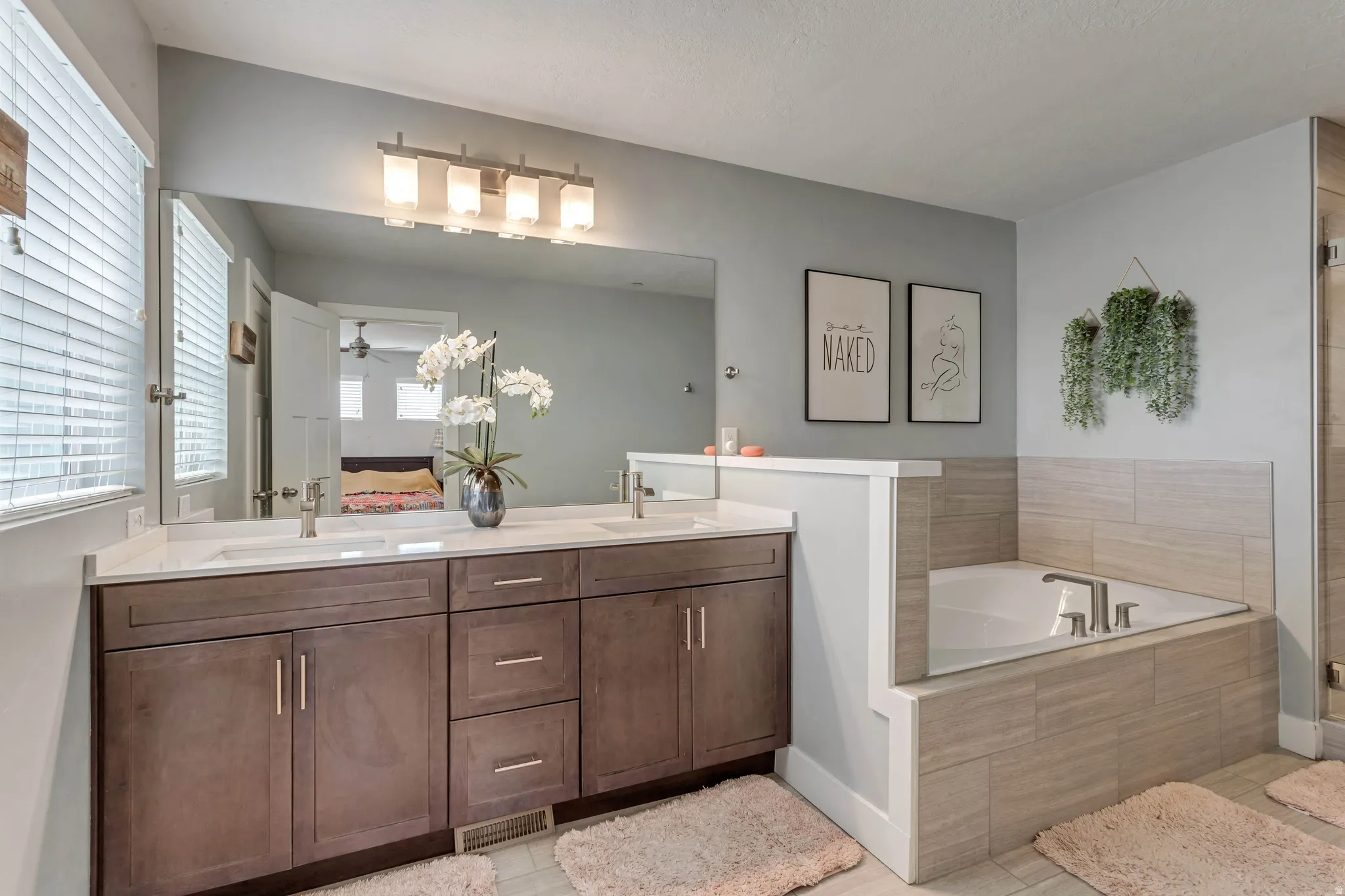 Ensuite bathroom featuring double vanity, a garden tub, a ceiling fan, and a shower stall