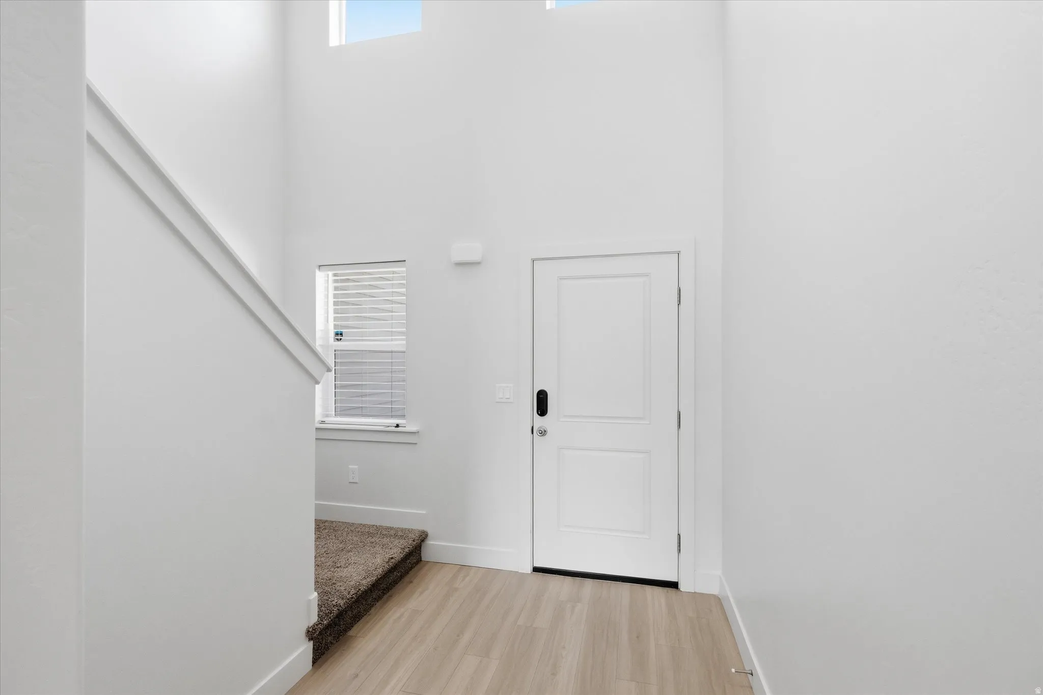 Entryway featuring healthy amount of natural light, light wood-style floors, and a high ceiling