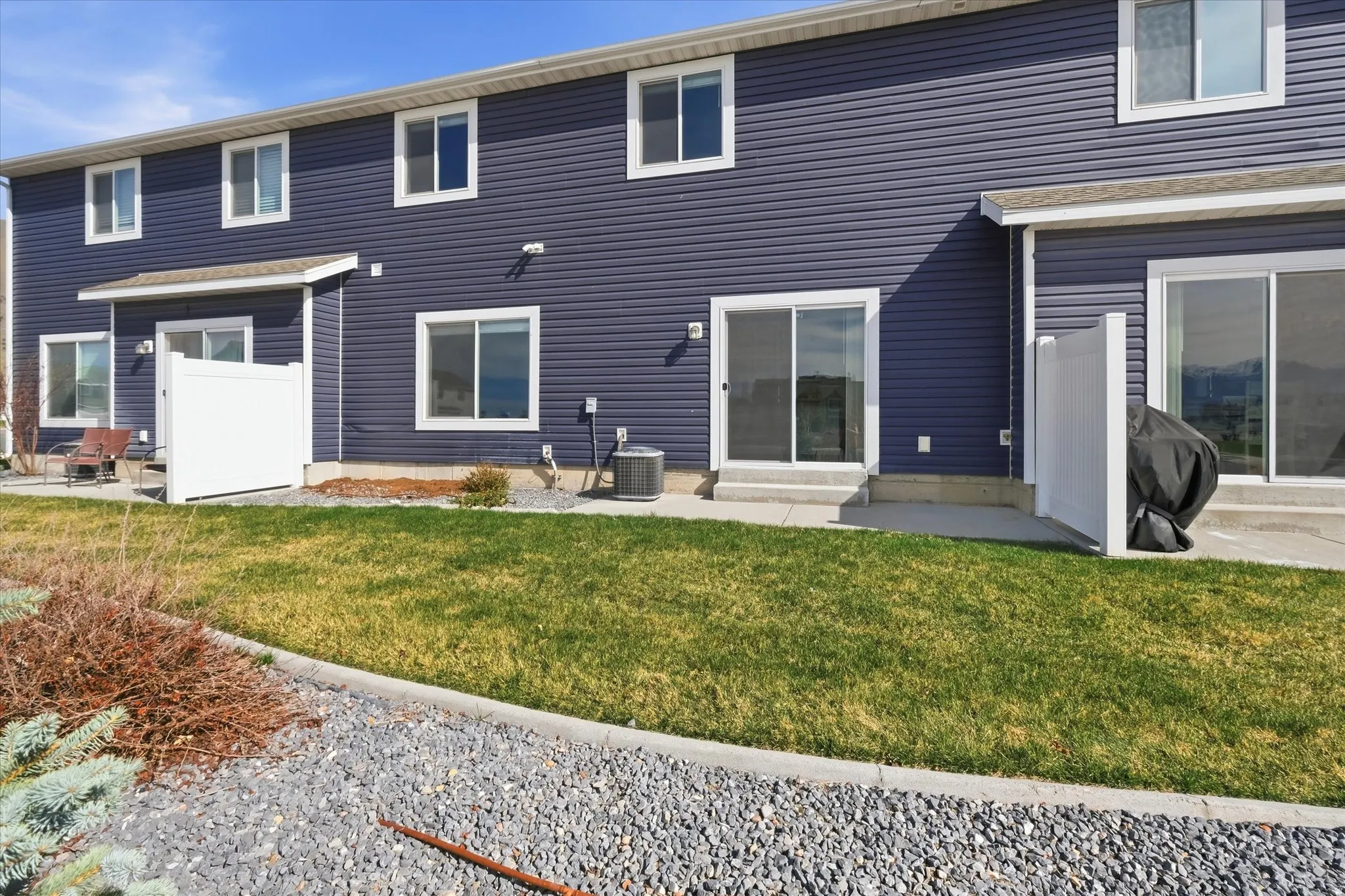 Rear view of house featuring a lawn, entry steps, and a patio area