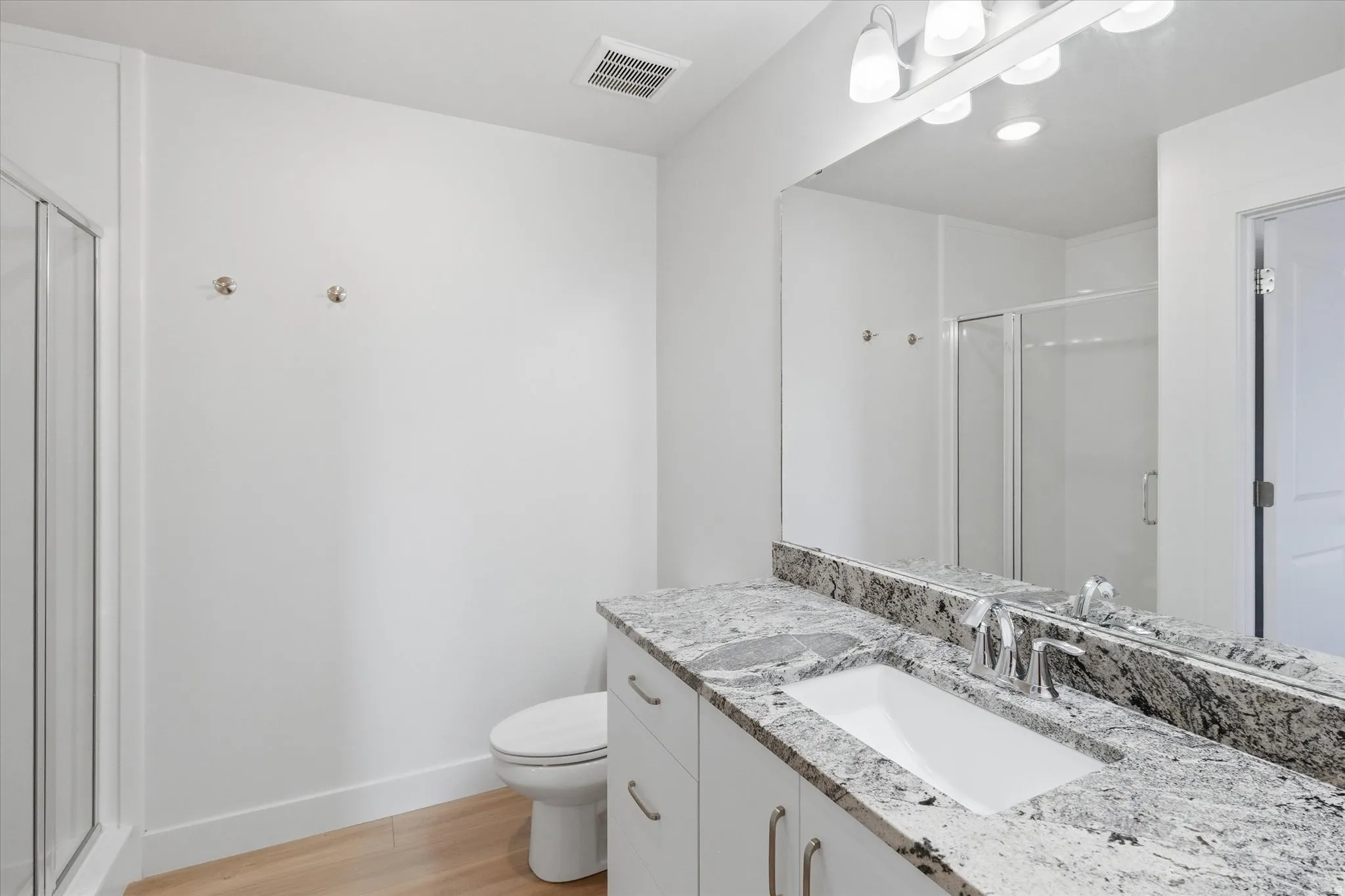 Primary Bathroom with a stall shower, vanity, and light wood-type flooring