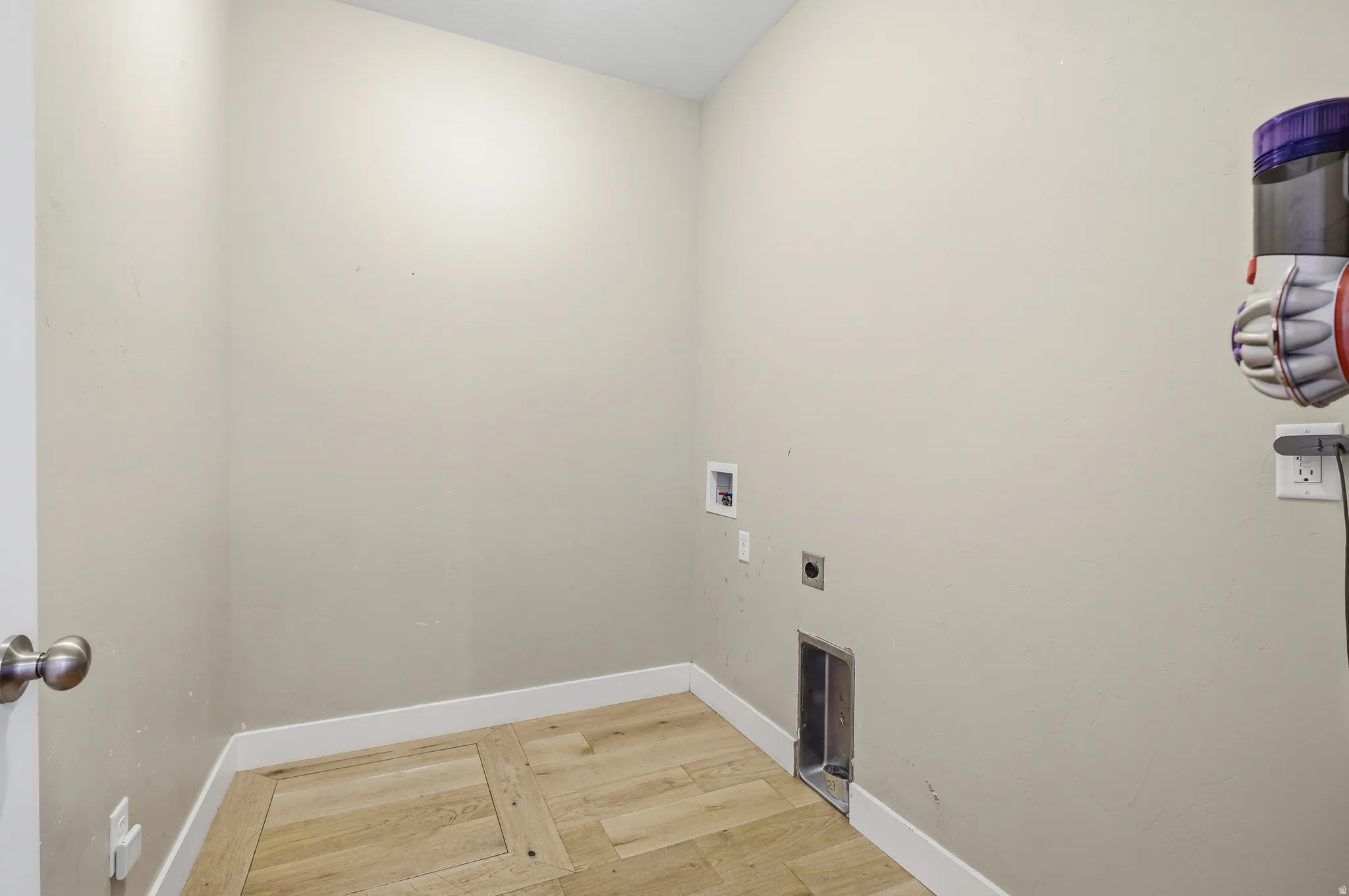 Laundry area with light-toned walls and wood-finish flooring