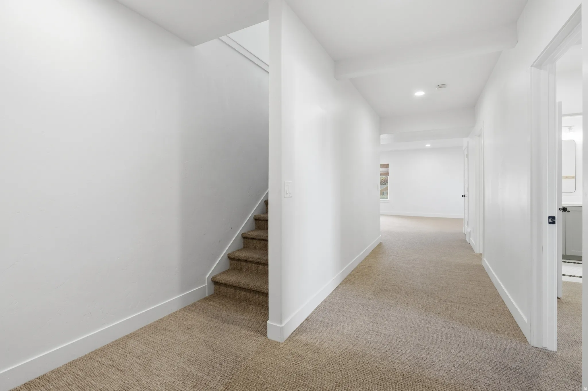 Carpeted hallway with white walls and baseboards