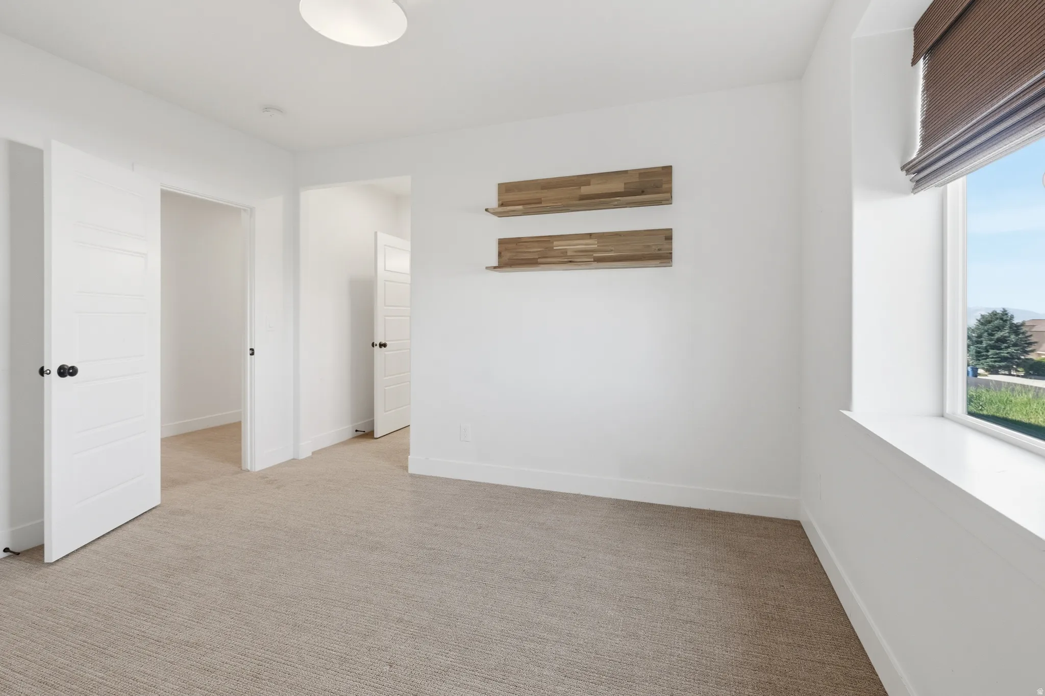 Neutral-toned carpeting extends throughout this interior space, featuring bright white walls and trim