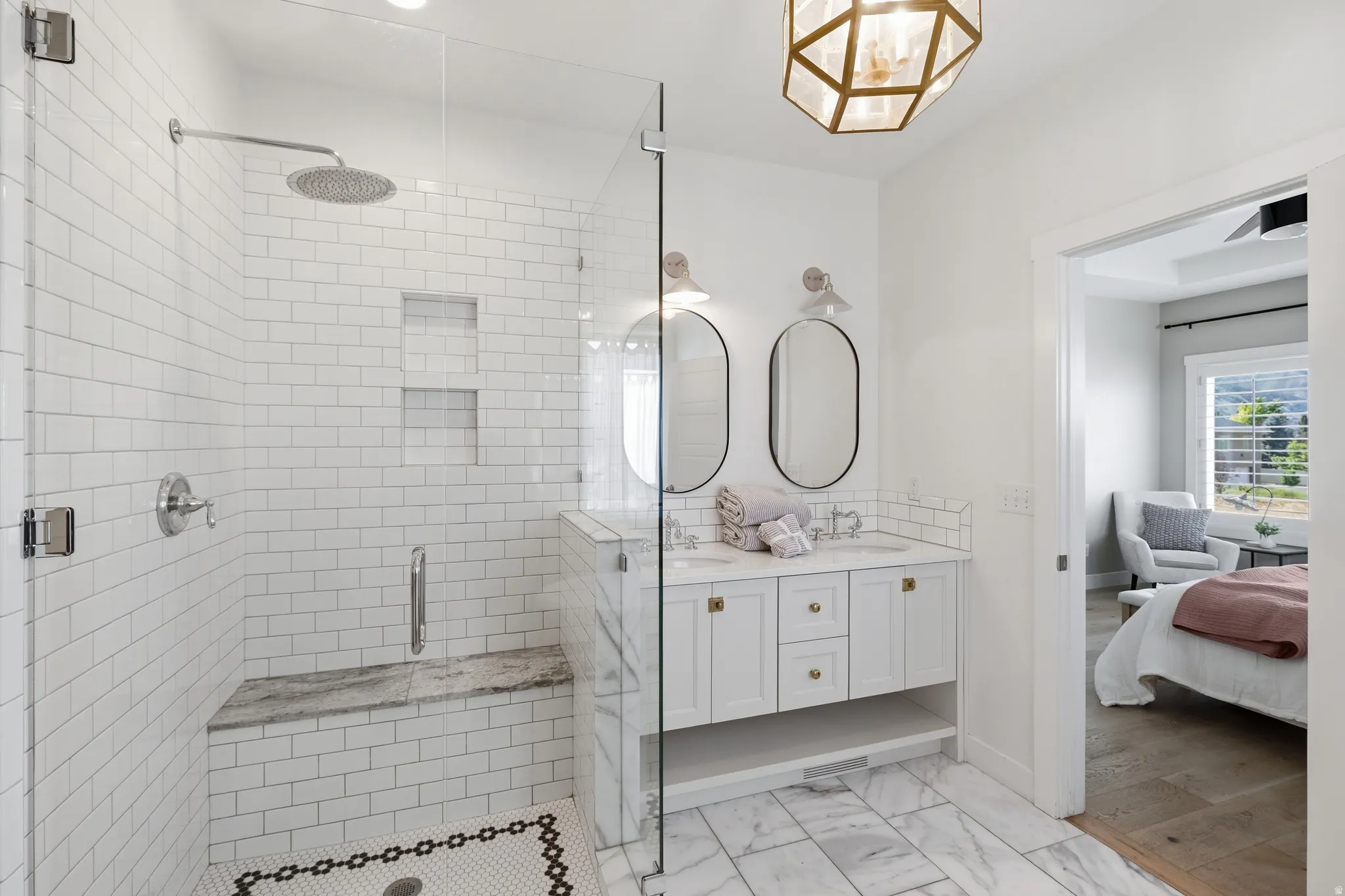 Spacious bathroom featuring a glass-enclosed shower with subway tile, a built-in shower bench, and dual wall niches