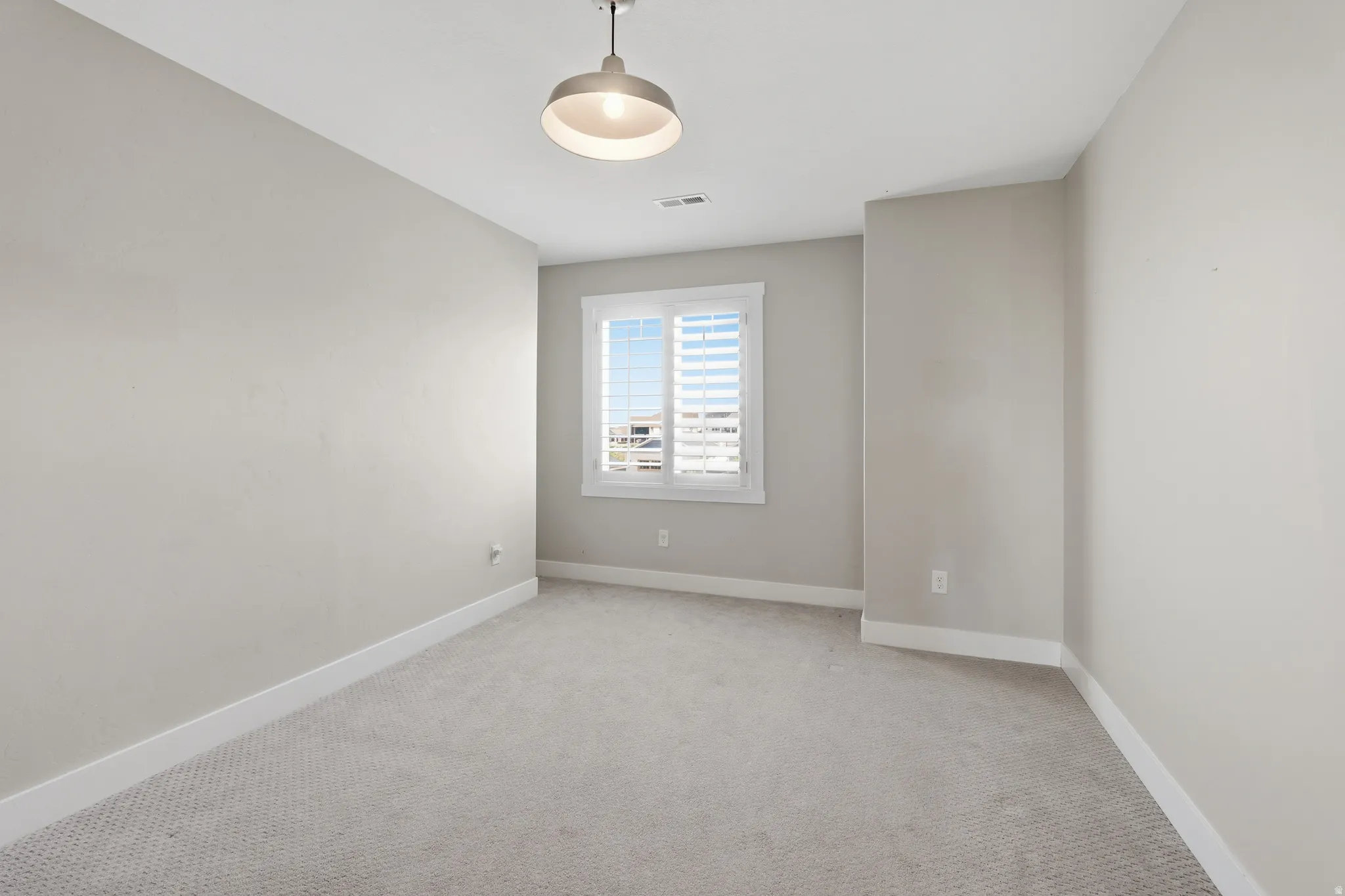 Carpeted room with a central ceiling light fixture, neutral wall paint, and white trim molding