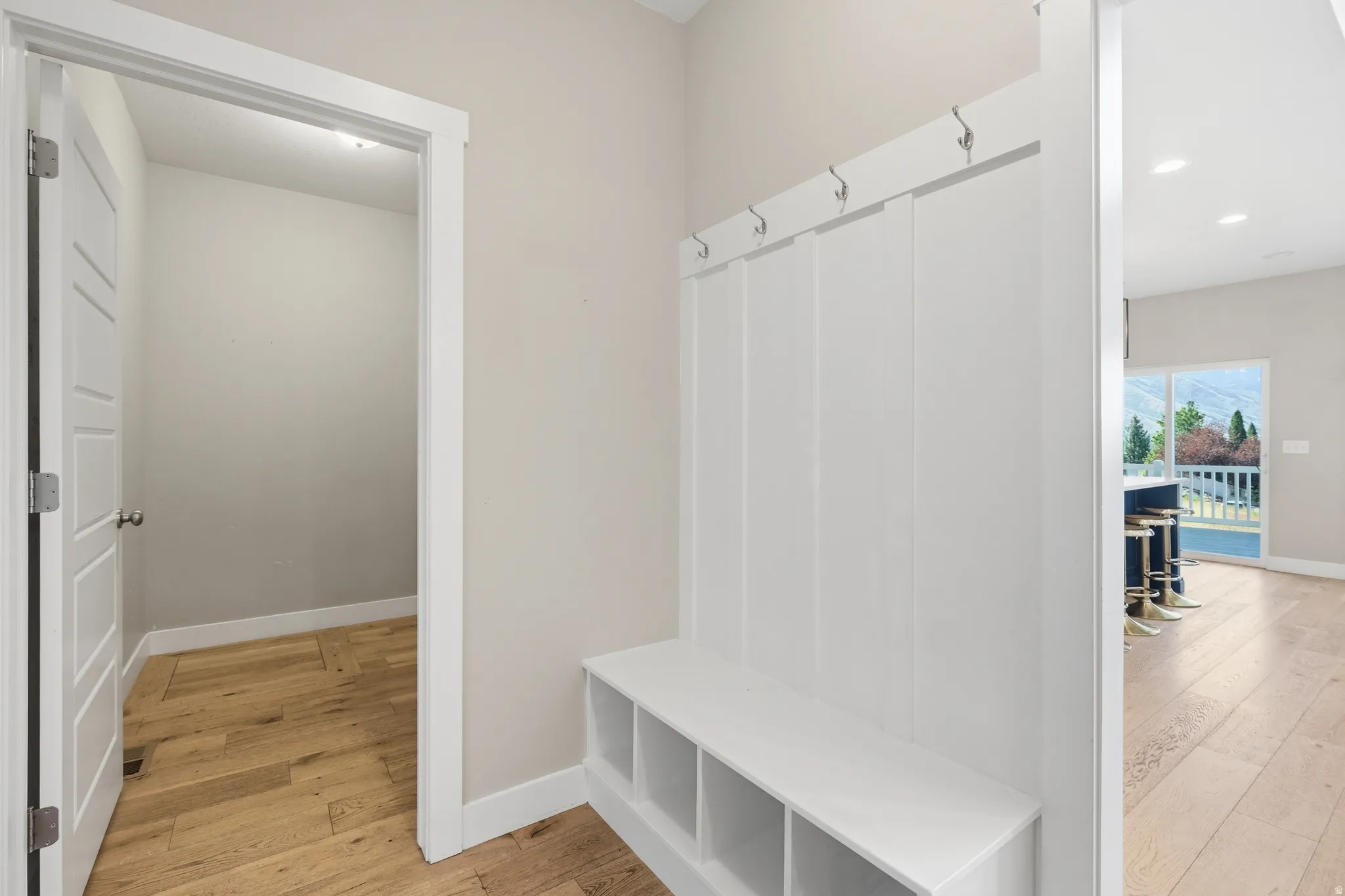 Entryway featuring a built-in bench with storage cubbies and coat hooks, wood-finish flooring, and a modern paneled door