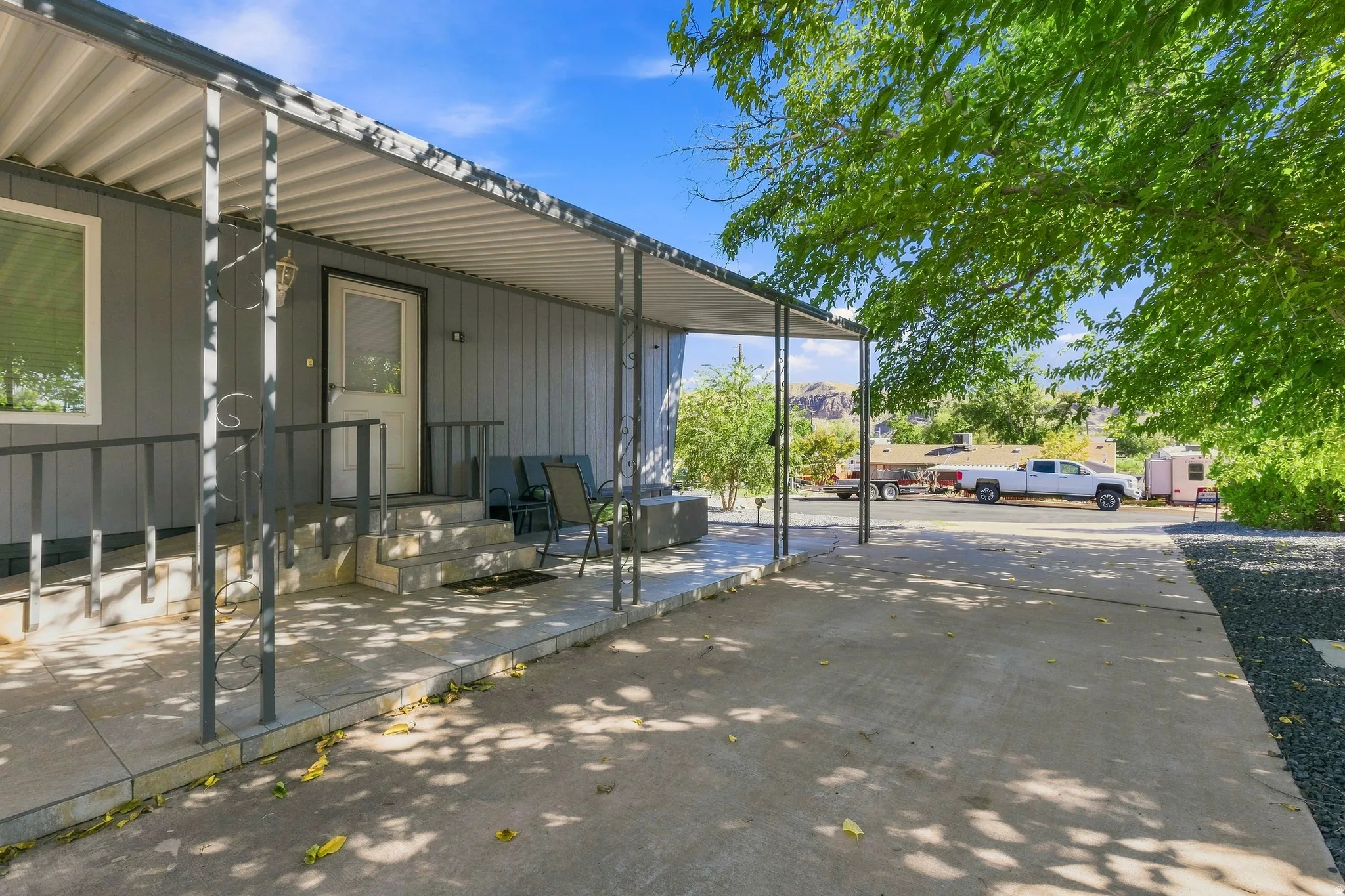 Covered front patio with gray vertical siding, concrete steps, and metal railings