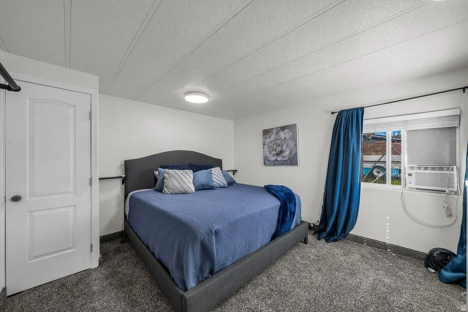 Bedroom featuring carpet flooring, a textured ceiling, and cooling unit