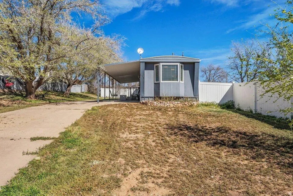 Manufactured / mobile home with a carport, driveway, and a porch