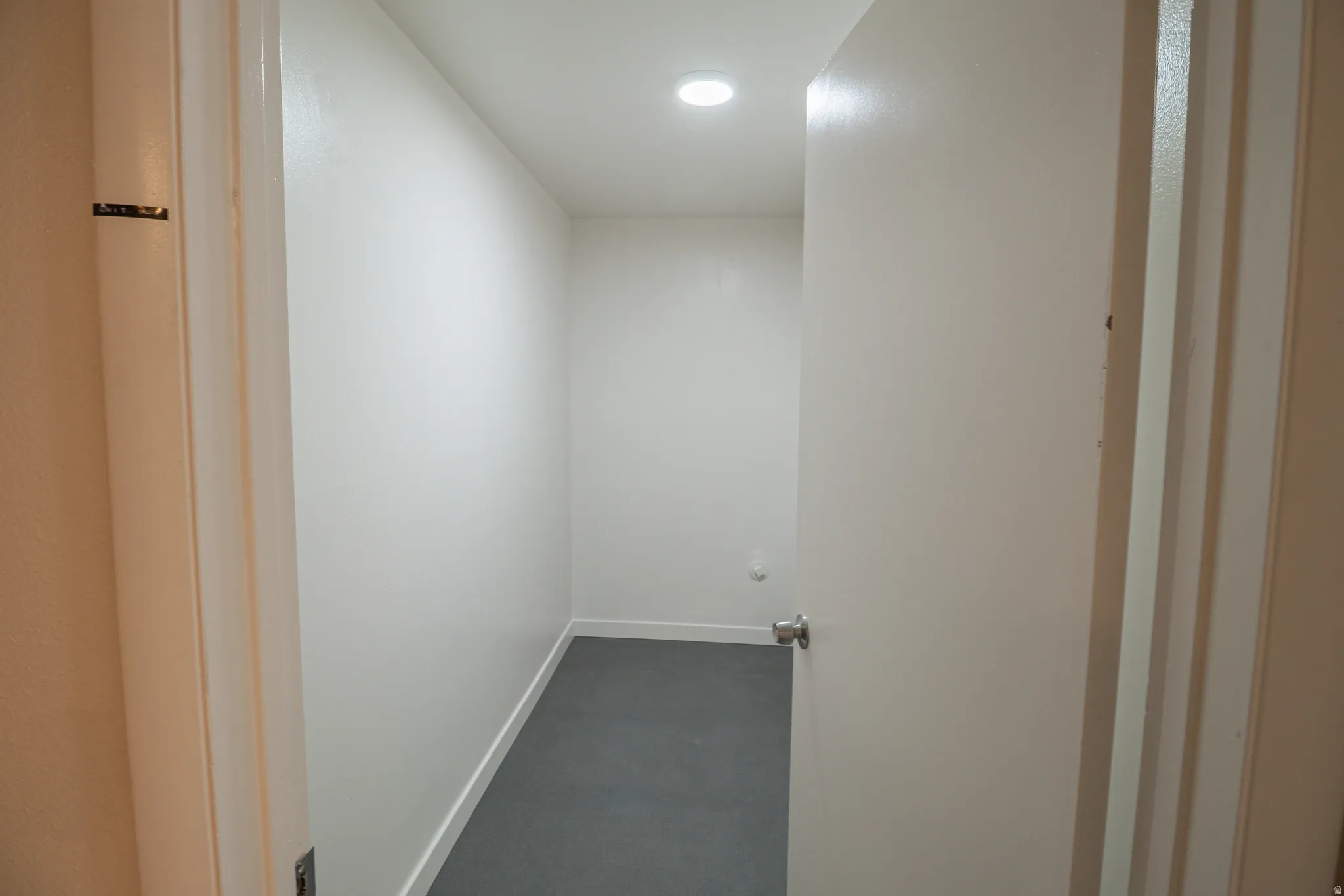 Hallway with dark carpet and baseboards