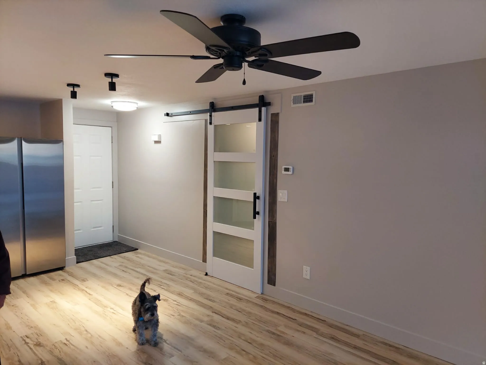 Empty room featuring a barn door, a ceiling fan, and light wood-style flooring