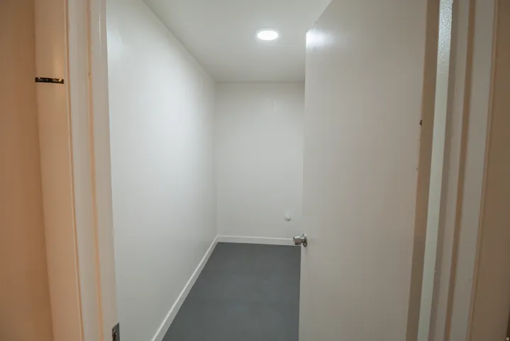 Hallway with dark carpet and baseboards