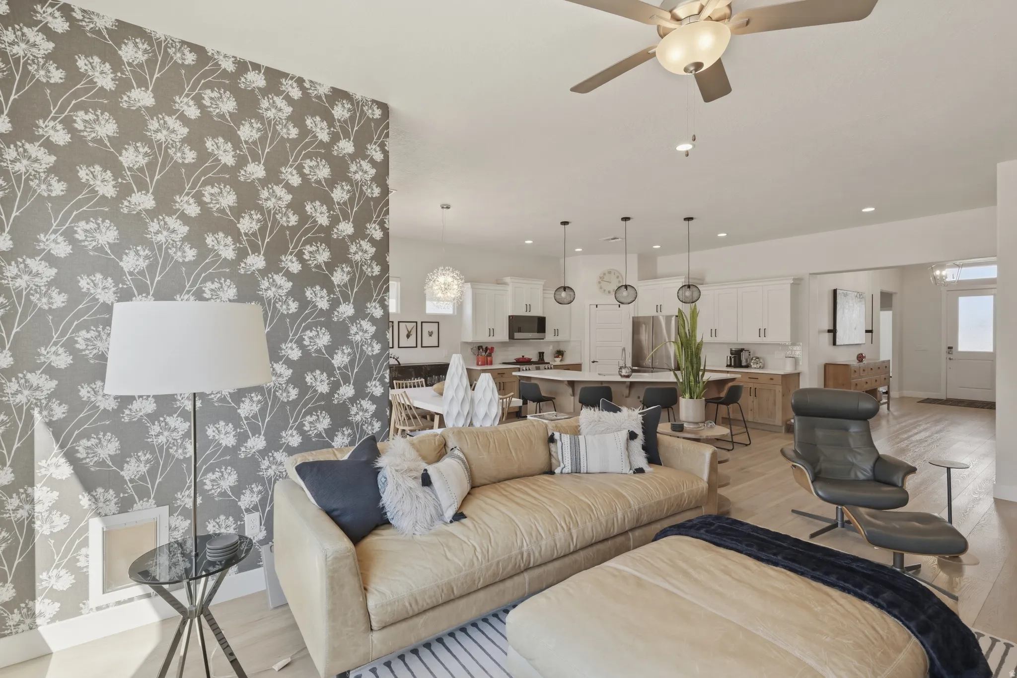 Living area featuring a ceiling fan, light wood finished floors, and a chandelier