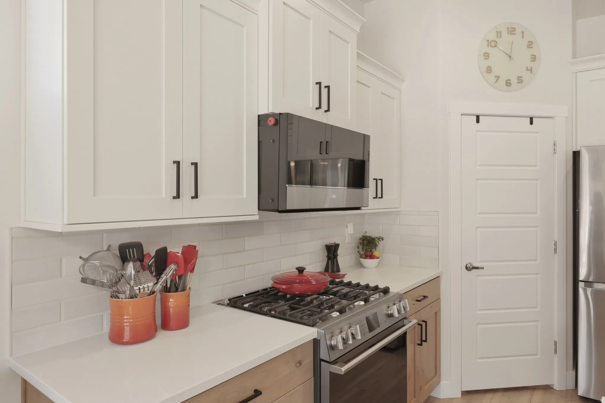 Kitchen featuring stainless steel appliances, white cabinetry, tasteful backsplash, and light stone countertops