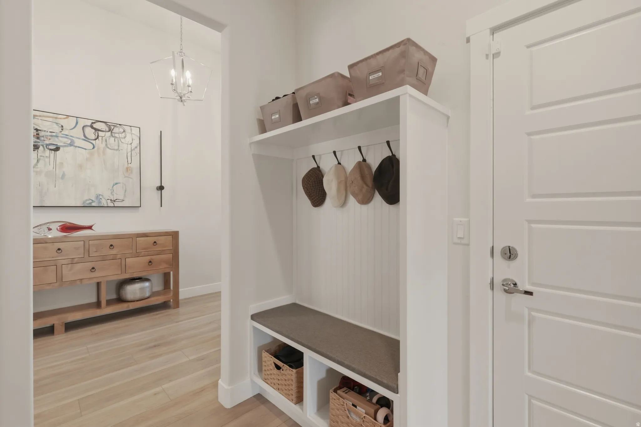 Mudroom with light wood-style flooring and a chandelier