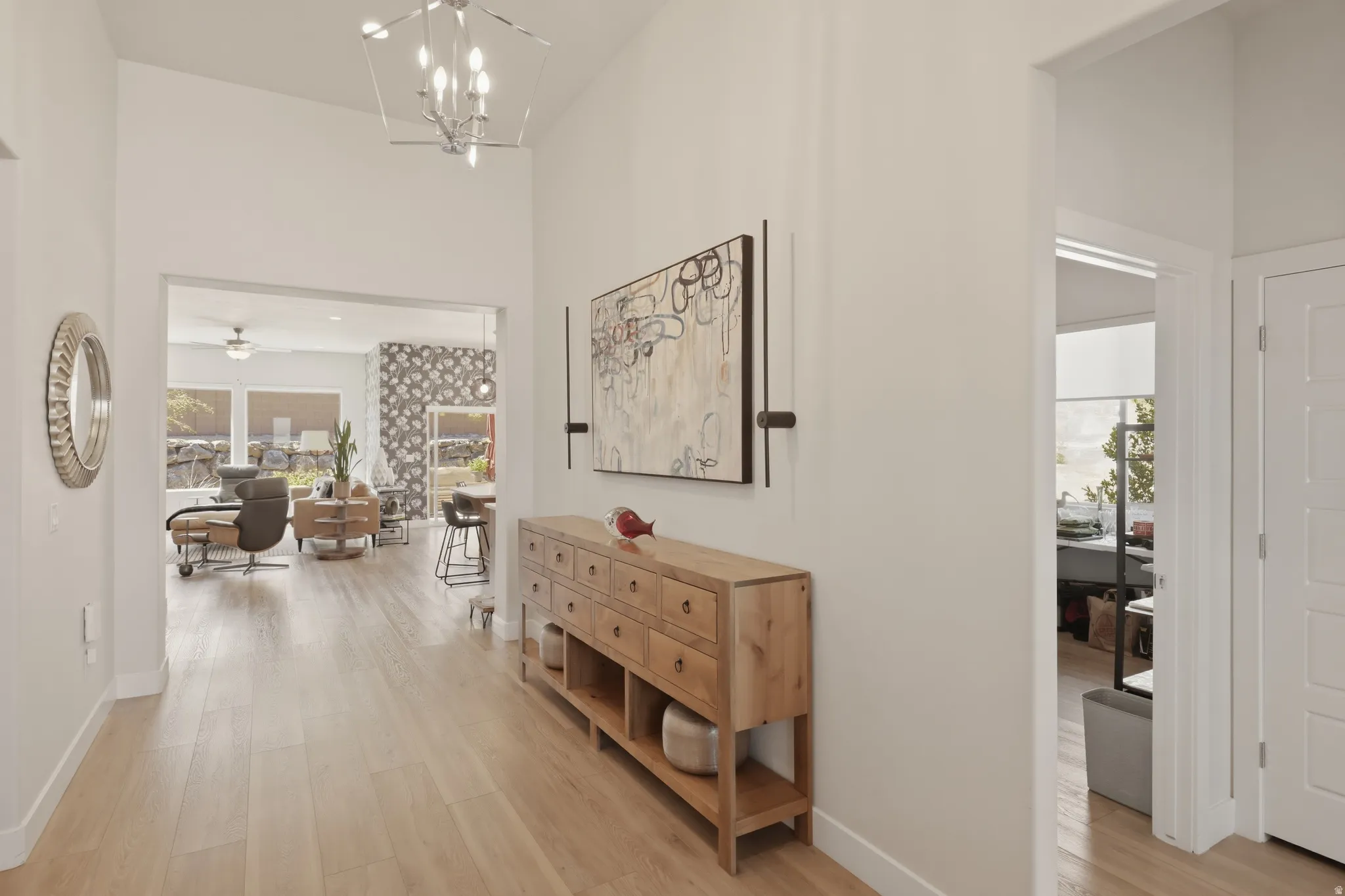 Hallway with light wood-style floors, a high ceiling, and suspended lighting