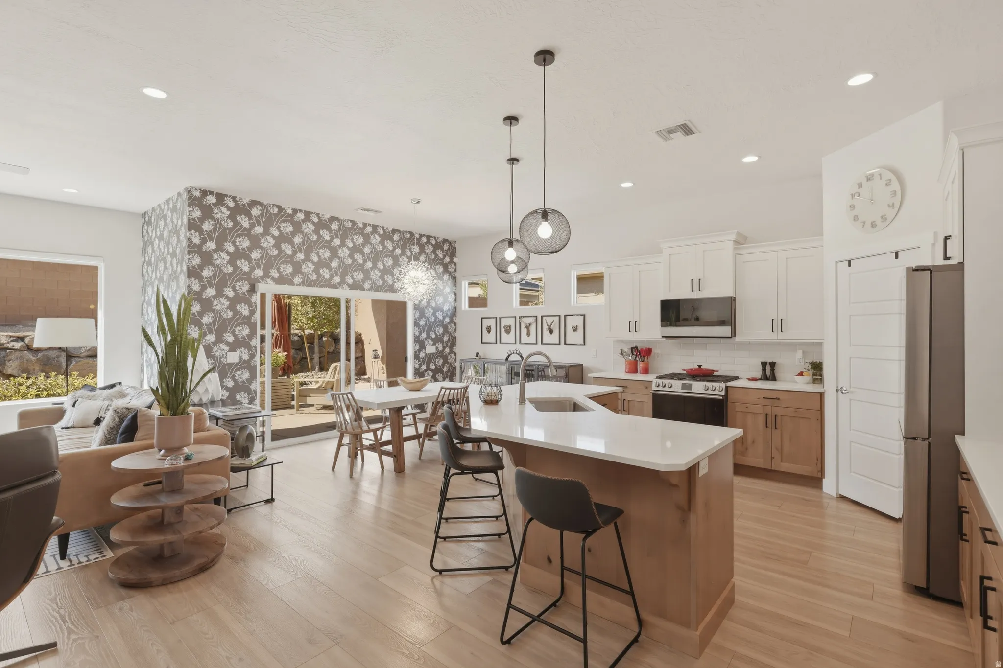 Kitchen featuring a breakfast bar area, stainless steel appliances, an island with sink, dual tone cabinetry, and light wood finished floors