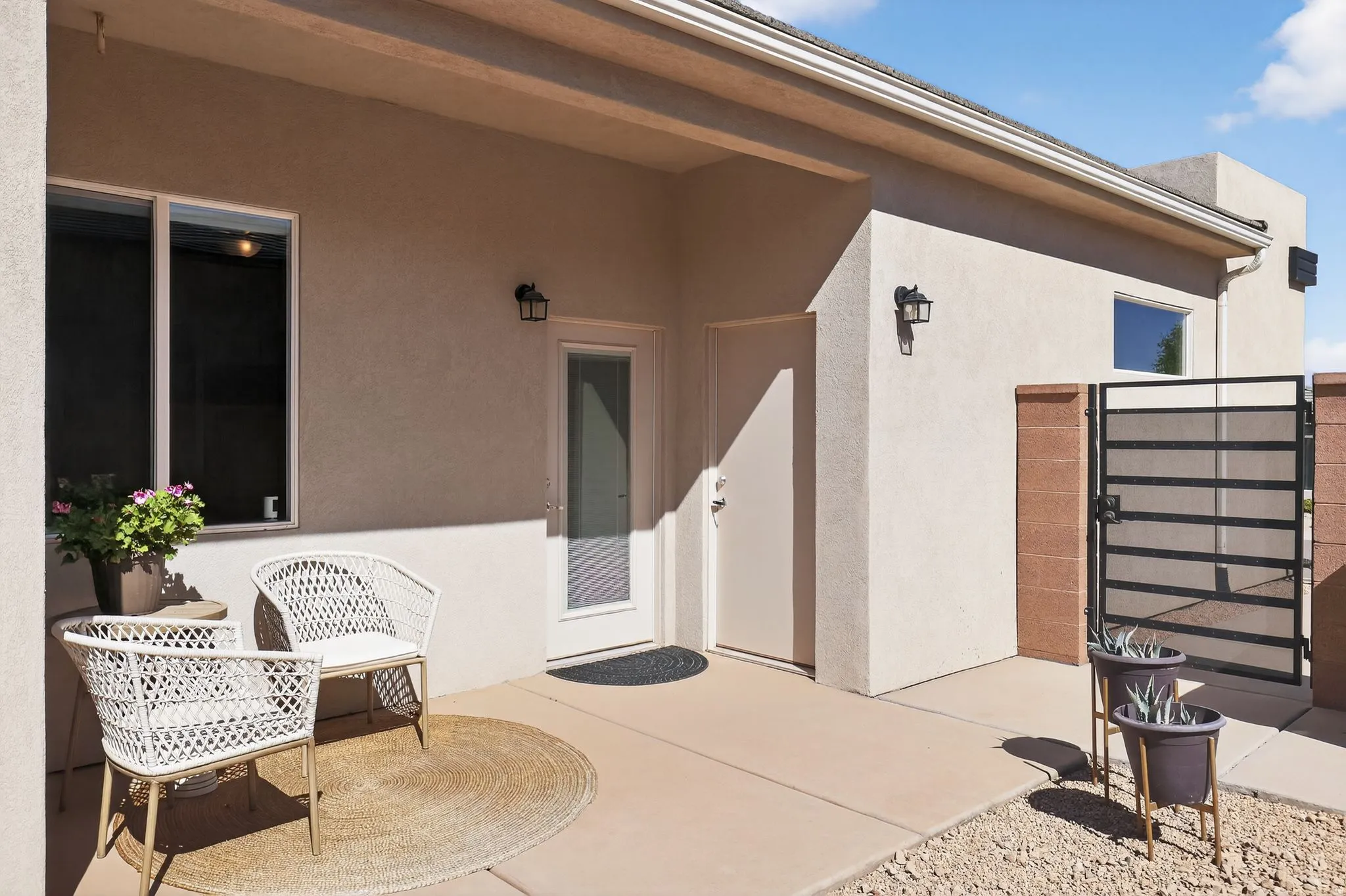 View of exterior entry featuring a patio area, stucco siding, and a gate