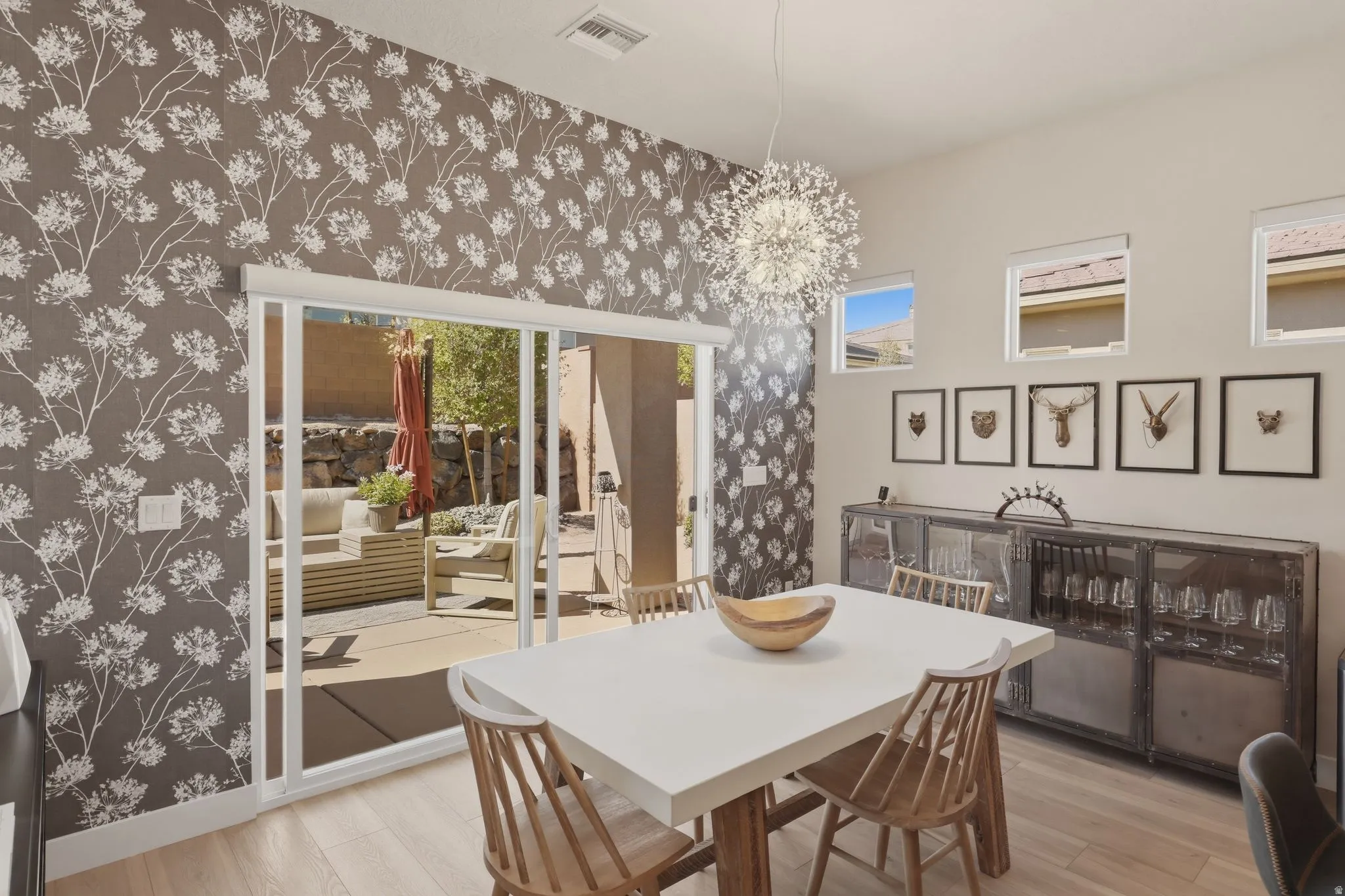 Dining space with suspended lighting, light wood finished floors, and wallpapered walls