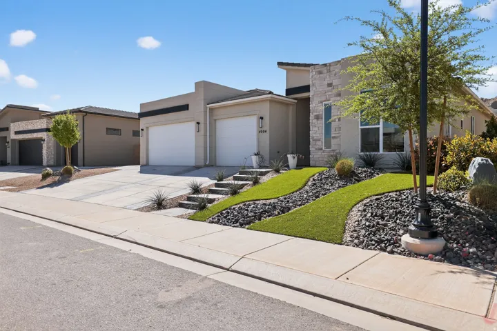 View of front of house with an attached garage, concrete driveway, and stucco siding