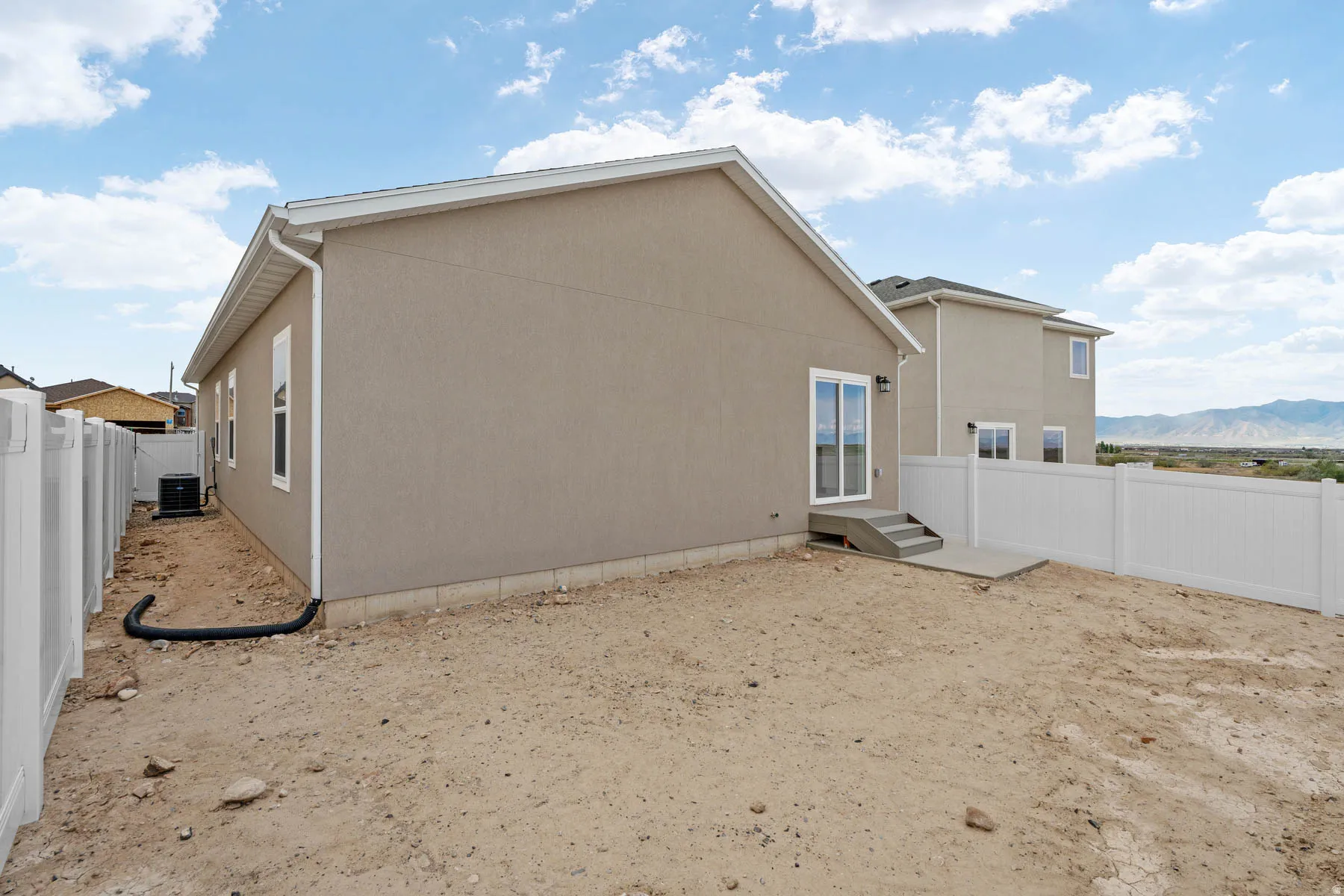 Rear exterior featuring stucco siding, white-trimmed windows, and a sliding glass door