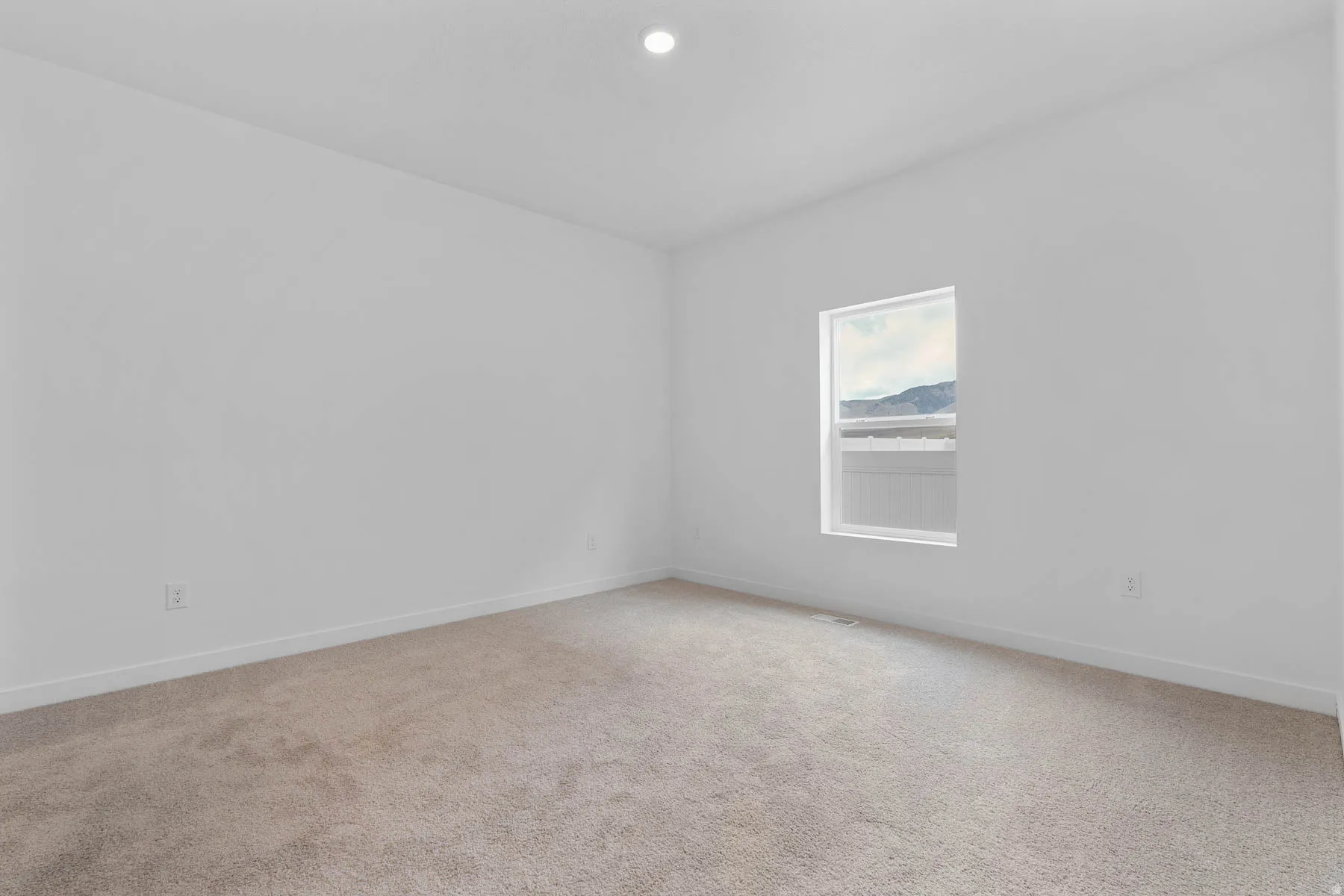 Bright room featuring neutral carpeting, white walls, a single window, and recessed ceiling lighting