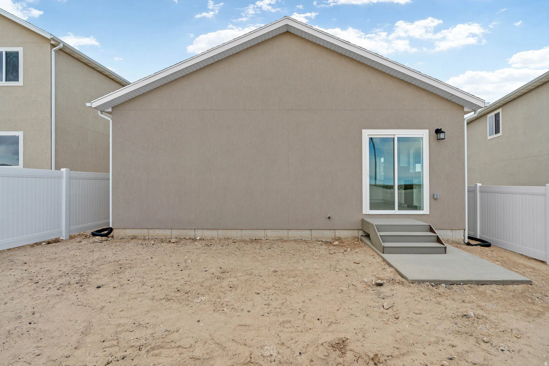 Rear exterior featuring a sliding glass door, concrete patio, and three-step concrete stairs