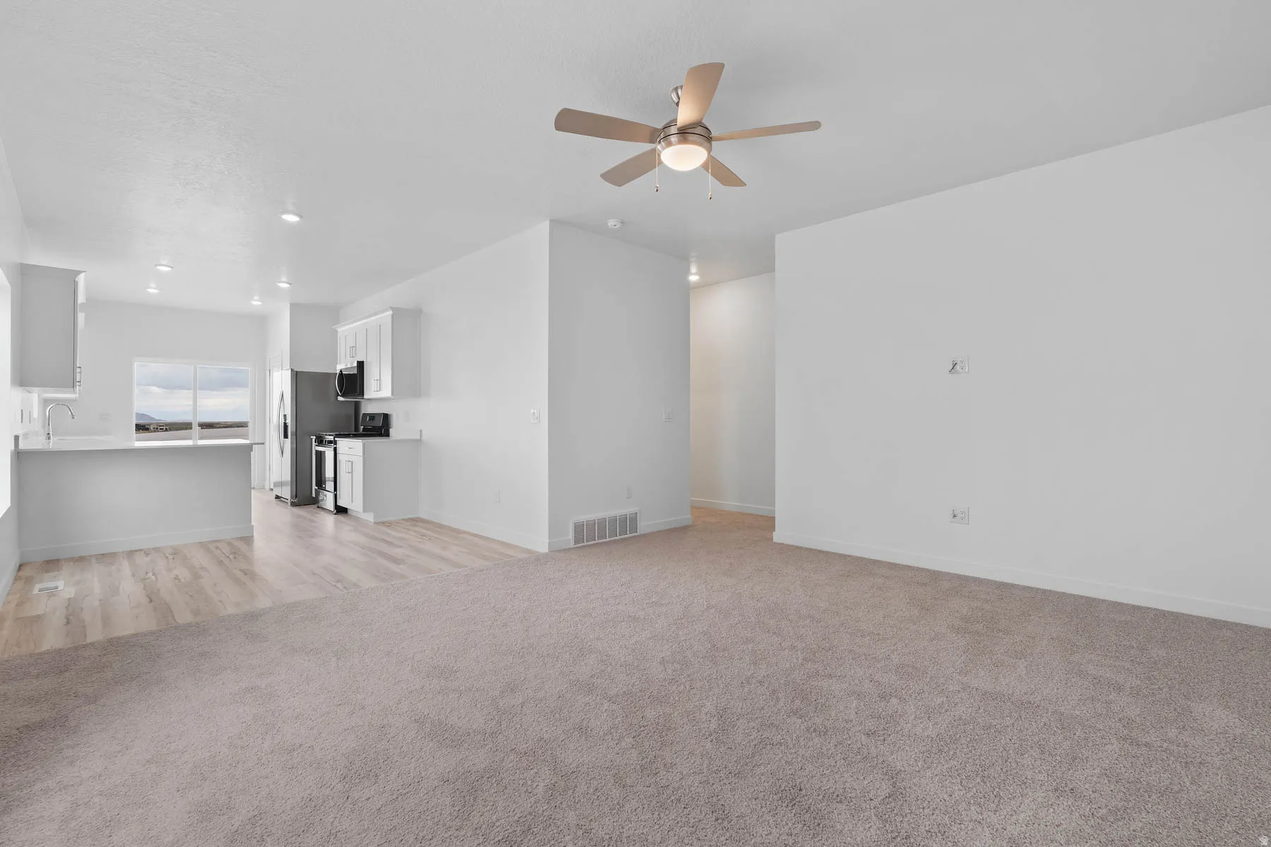 Expansive open-concept living area featuring a ceiling fan with integrated lighting