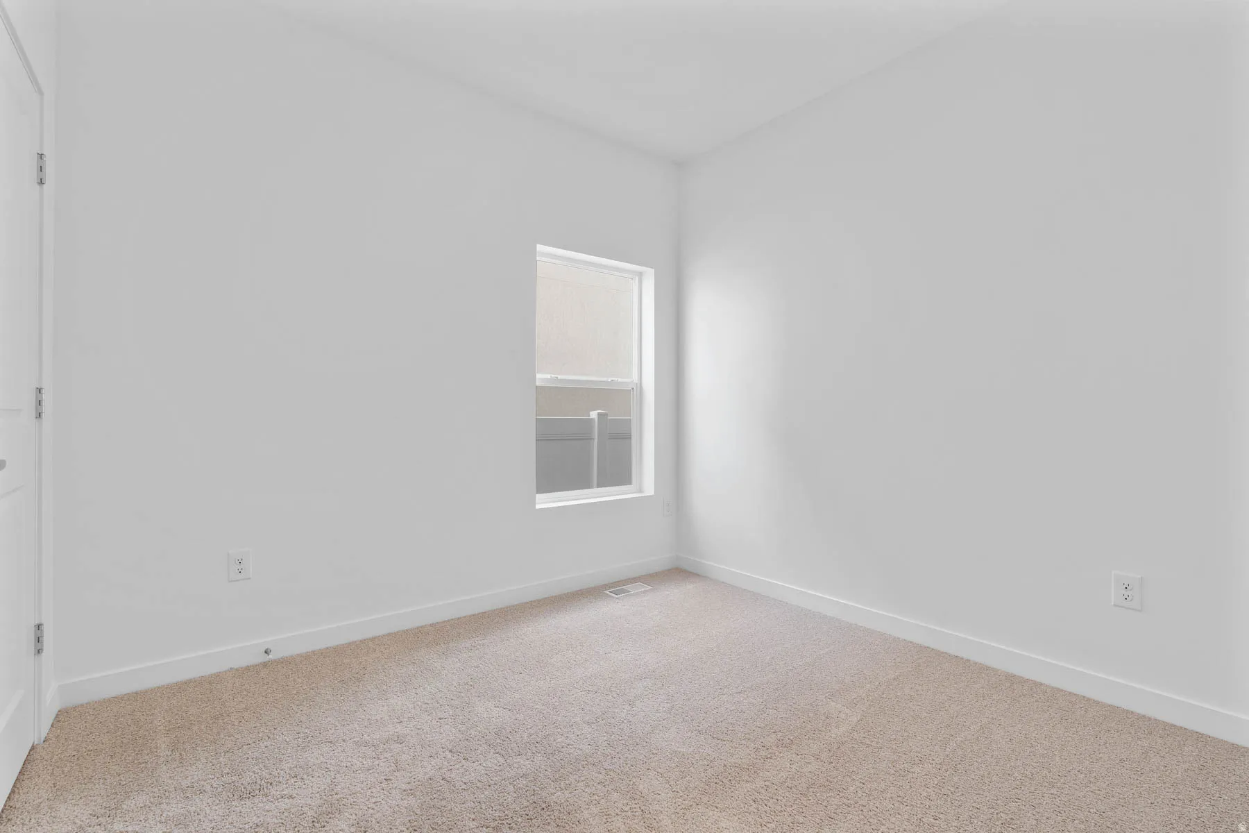Neutral color palette room featuring light-toned carpet flooring and a single window with blinds