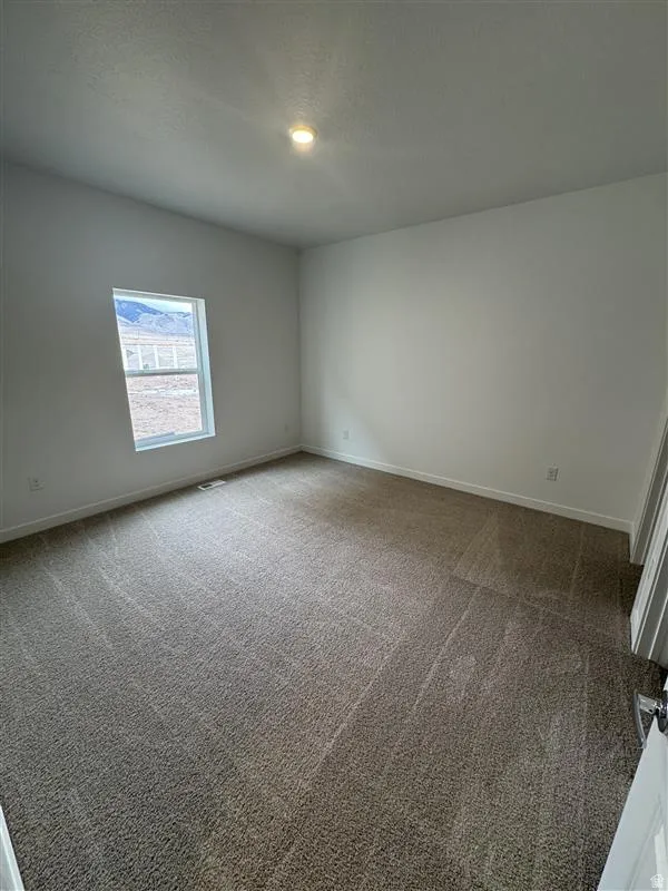 Carpeted empty room featuring baseboards and a textured ceiling