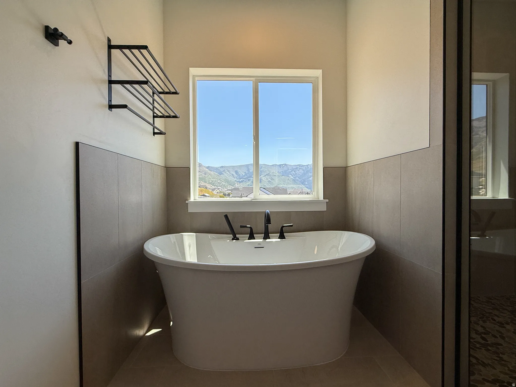 Full bath with a soaking tub, tile patterned flooring, and wainscoting