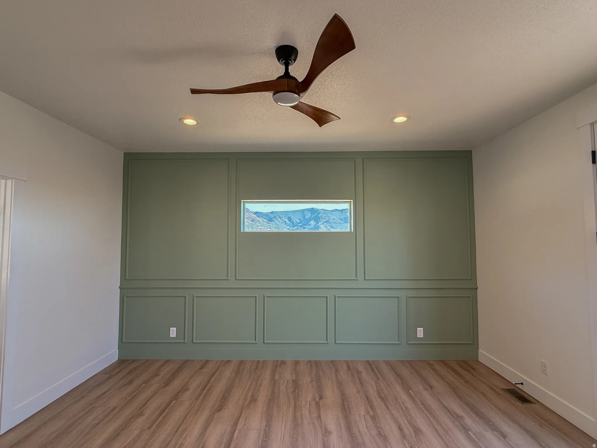 Unfurnished room with light wood finished floors, ceiling fan, a decorative wall, a textured ceiling, and recessed lighting