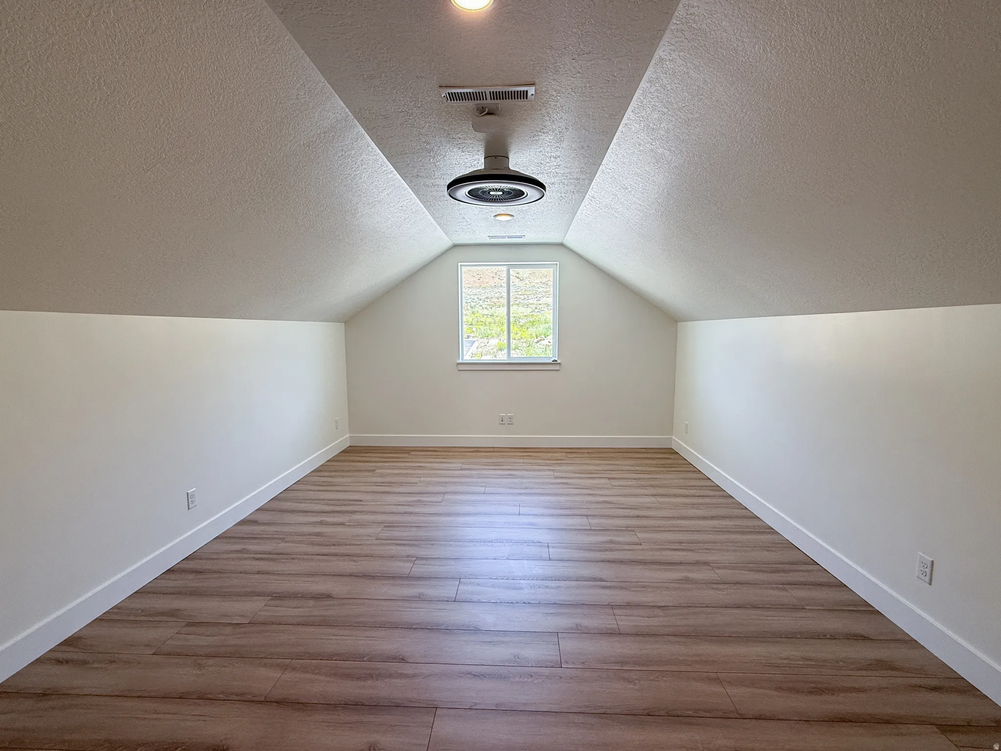 Additional living space with light wood-type flooring and a textured ceiling