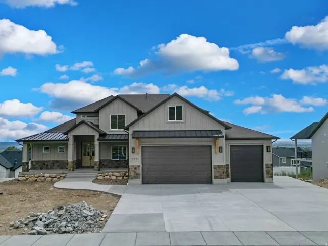 View of front of house with a standing seam roof, concrete driveway, a garage, board and batten siding, and a shingled roof