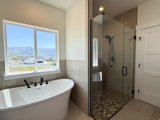 Bathroom with a freestanding tub, a shower stall, a mountain view, wainscoting, and recessed lighting