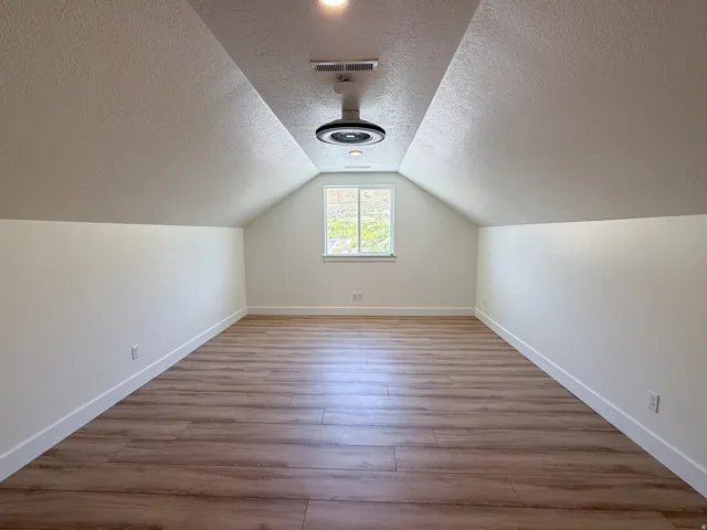 Additional living space with light wood-type flooring and a textured ceiling