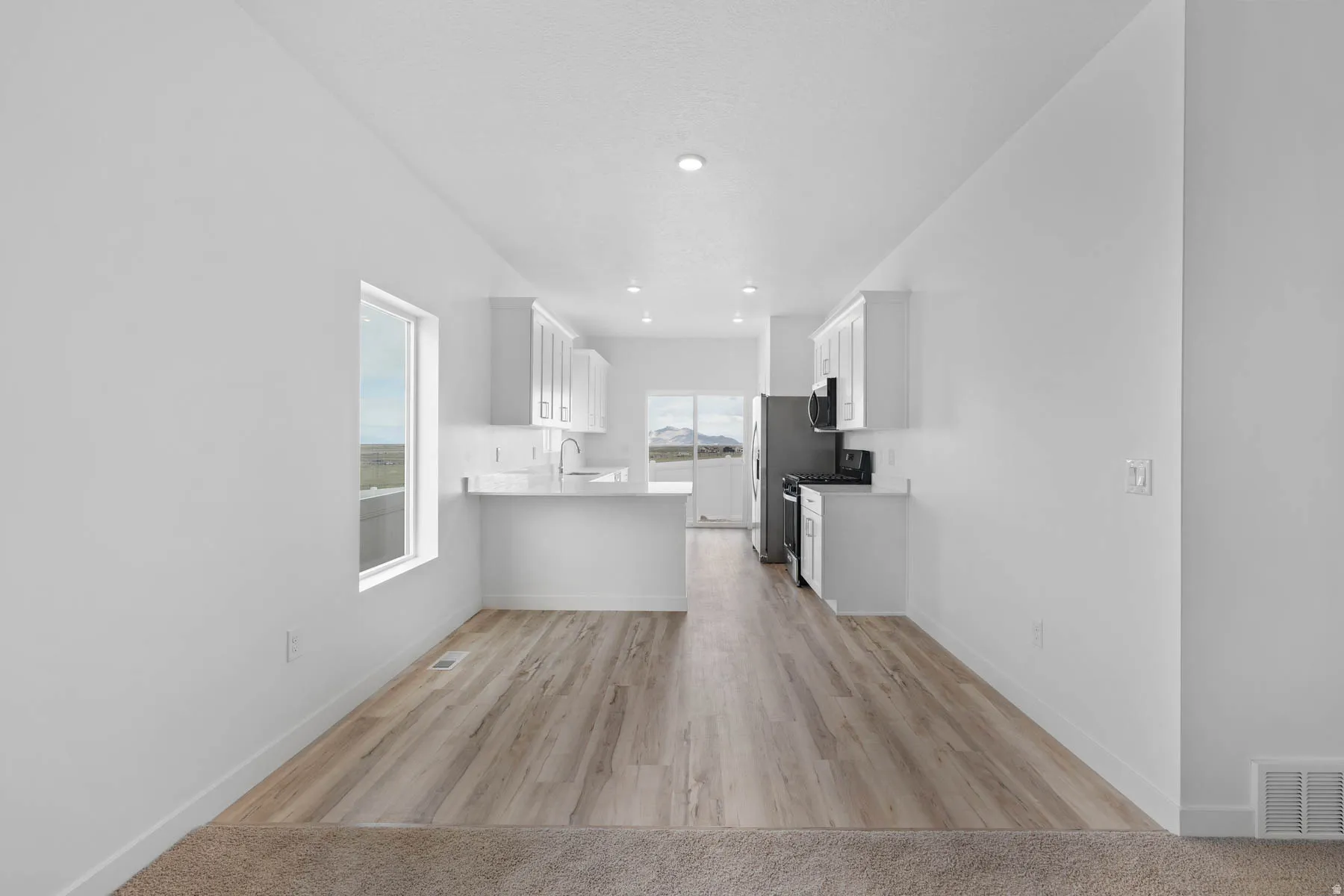 Open-concept living space featuring wood-finish flooring, white walls, and recessed lighting