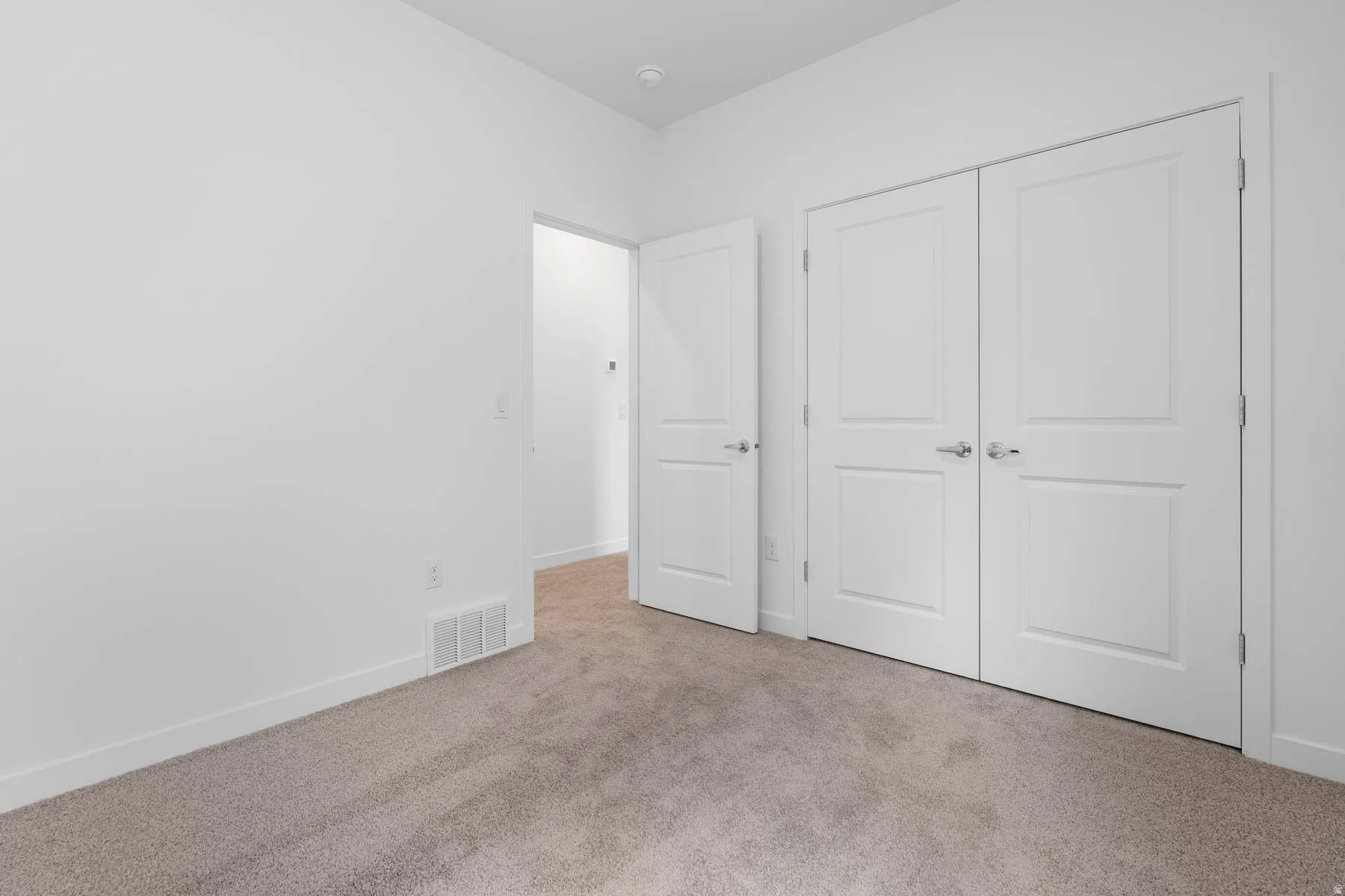Neutral tone-on-tone carpeting complements the bright white walls and trim