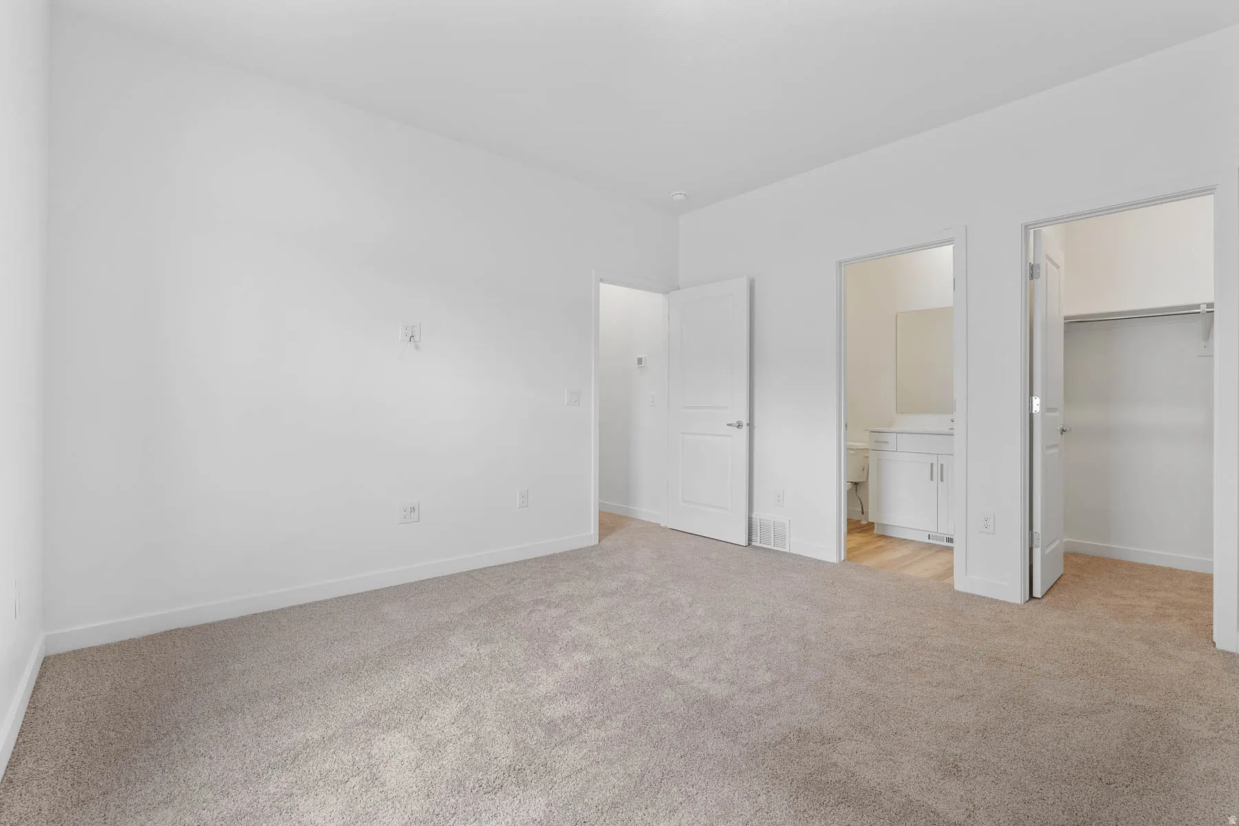 Carpeted room with white walls, two interior doors, and baseboard trim
