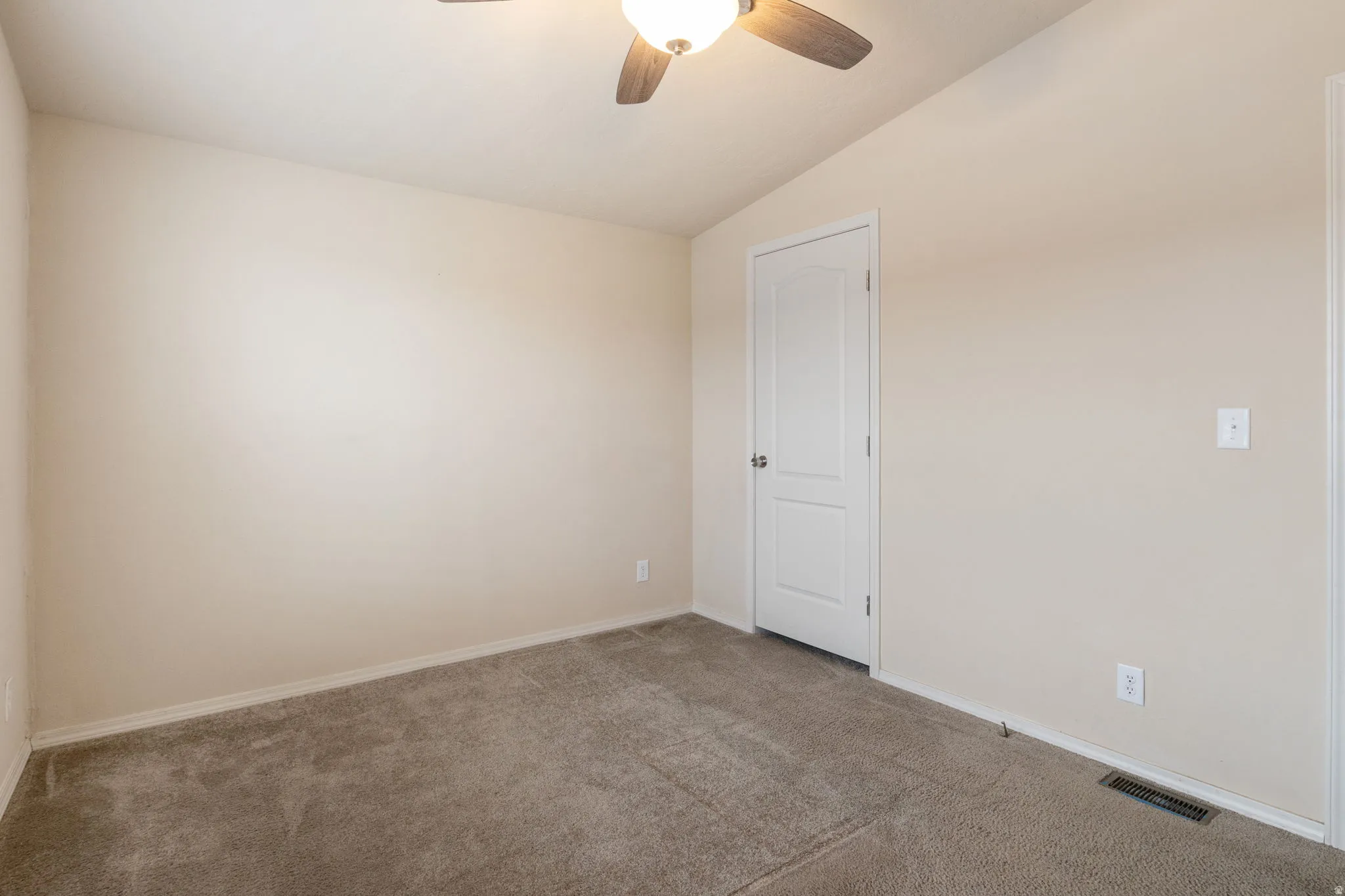 Spare room with vaulted ceiling, carpet flooring, and ceiling fan