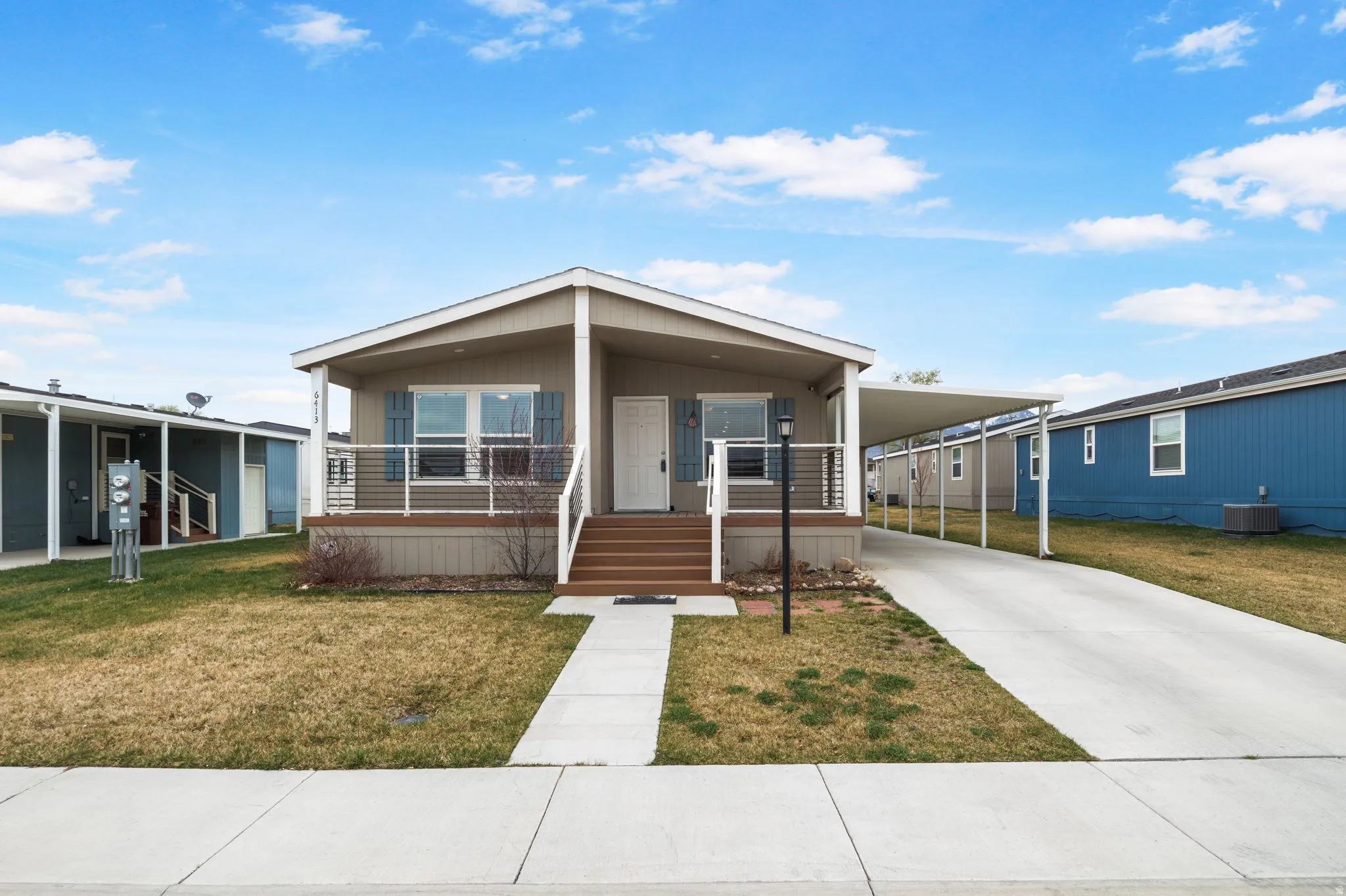 Manufactured / mobile home with a carport, covered porch, a front lawn, and driveway