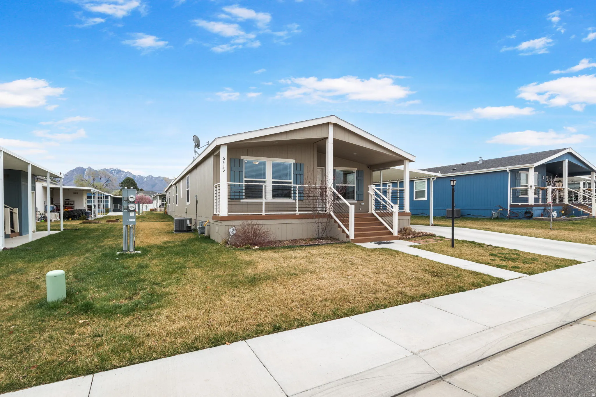 Manufactured / mobile home featuring covered porch, a mountain view, a front lawn, and concrete driveway