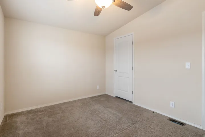 Spare room with vaulted ceiling, carpet flooring, and ceiling fan